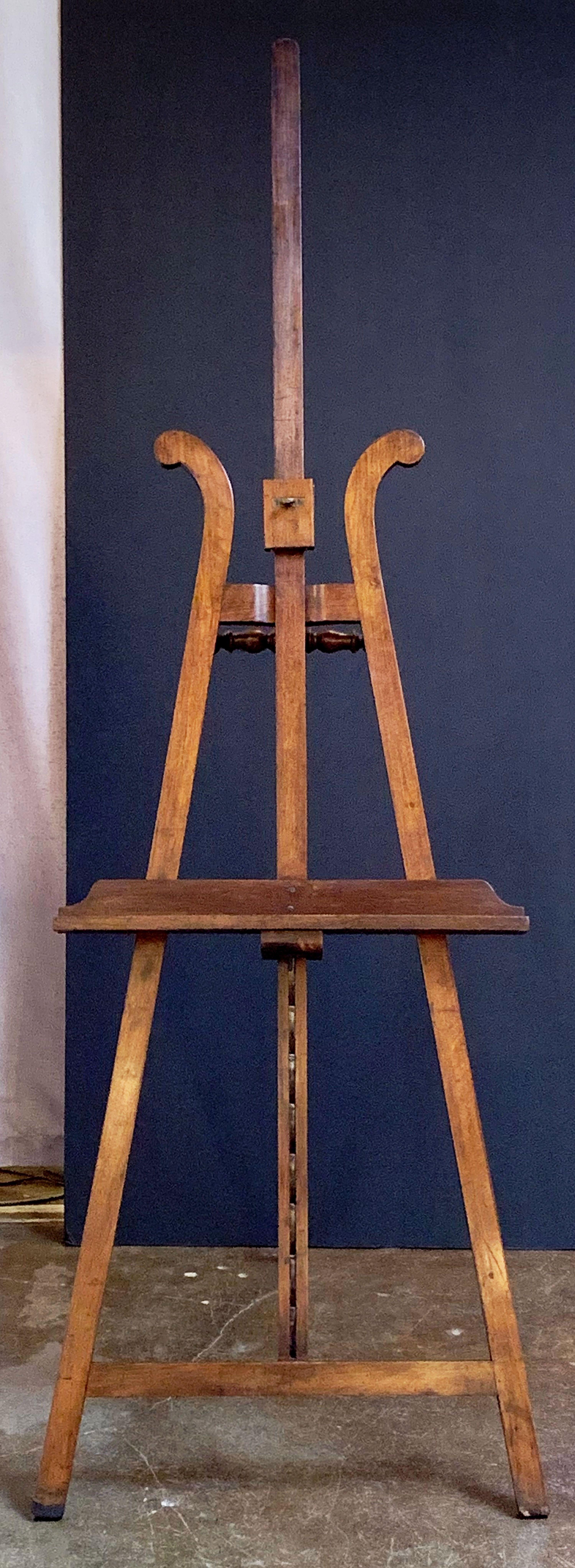 A handsome French artist's gallery display or studio floor easel from the 19th century, featuring a sliding mahogany and brass mechanism to adjust the tray height, with turned mahogany accents to the top and back.

Dimensions are: Max H 96 inches