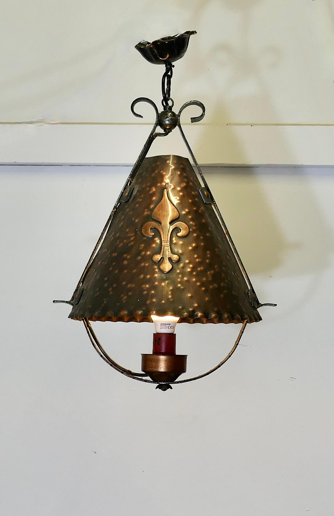 French Arts and Crafts Gothic Copper Lantern

A very unusual light, the light is a Conical shape and made in hand beaten copper with a large Fleure de Lys emblem on each side. The shade sits in a wrought iron frame which hangs from an iron ceiling