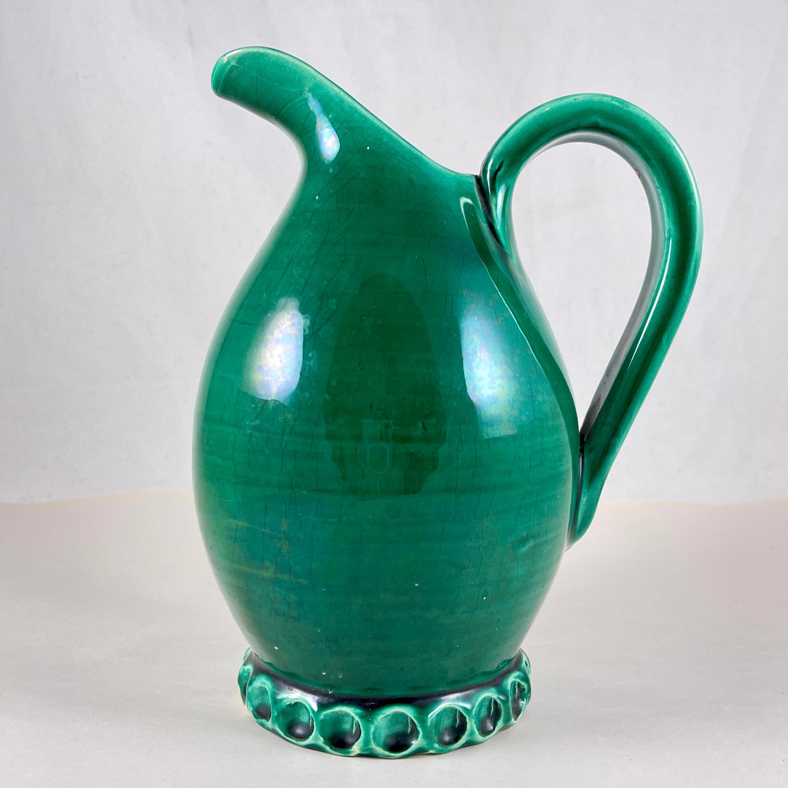
From the Atelier Cérenne à Vallauris in France, a rustic hand made pottery wine jug, circa 1940-1950.

The atelier was known for its small, high-end production runs designed by Charles René Neveux.

Glazed in the Provençal Green popular in Southern