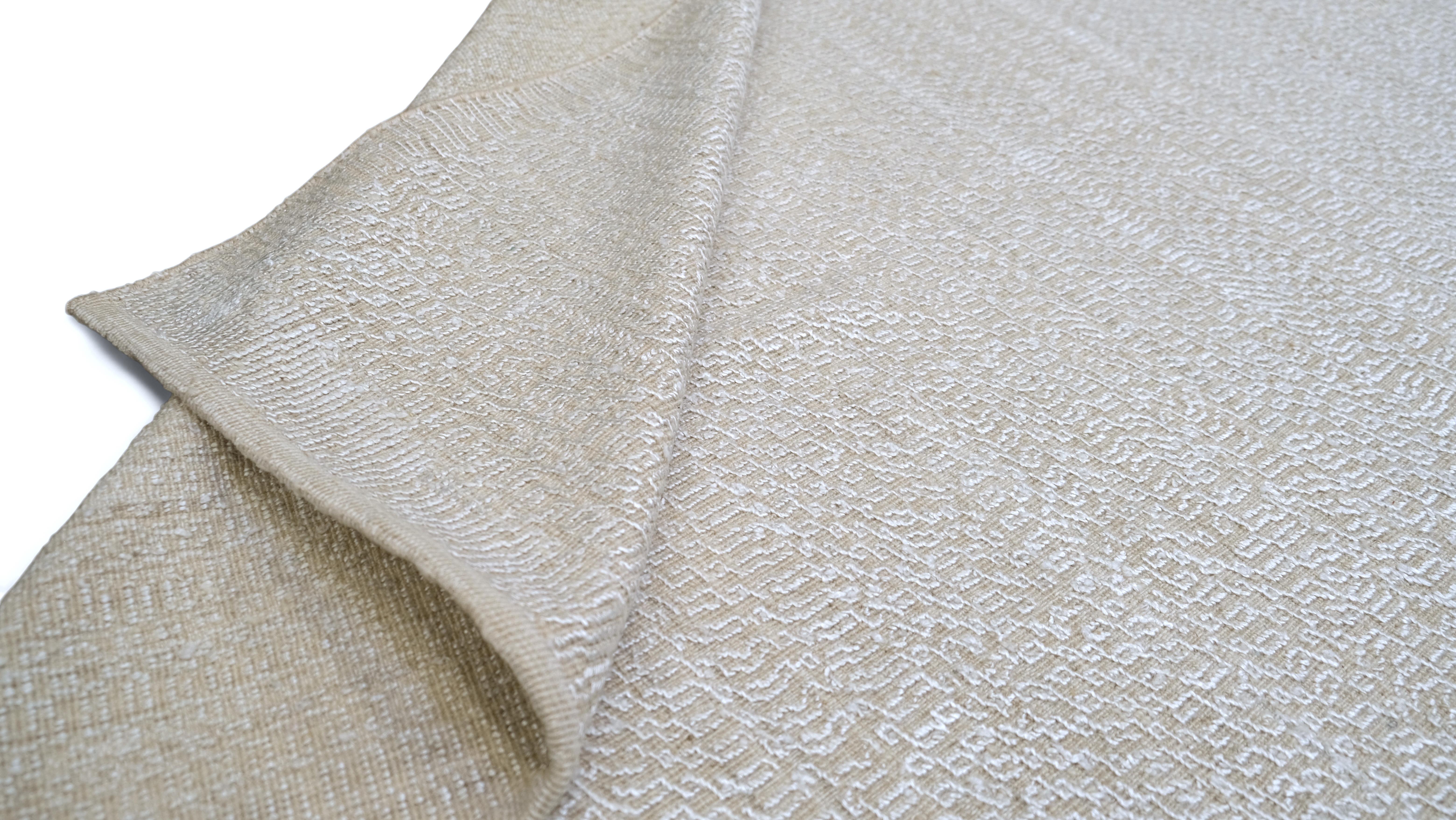 Dieser exquisite handgeknüpfte Teppich aus Wolle und Kunstseide verleiht Ihrem Zuhause einen Hauch von dezentem Luxus. Mit seinem minimalistischen elfenbeinfarbenen Design strahlt dieser Teppich Raffinesse und Vielseitigkeit aus und fügt sich
