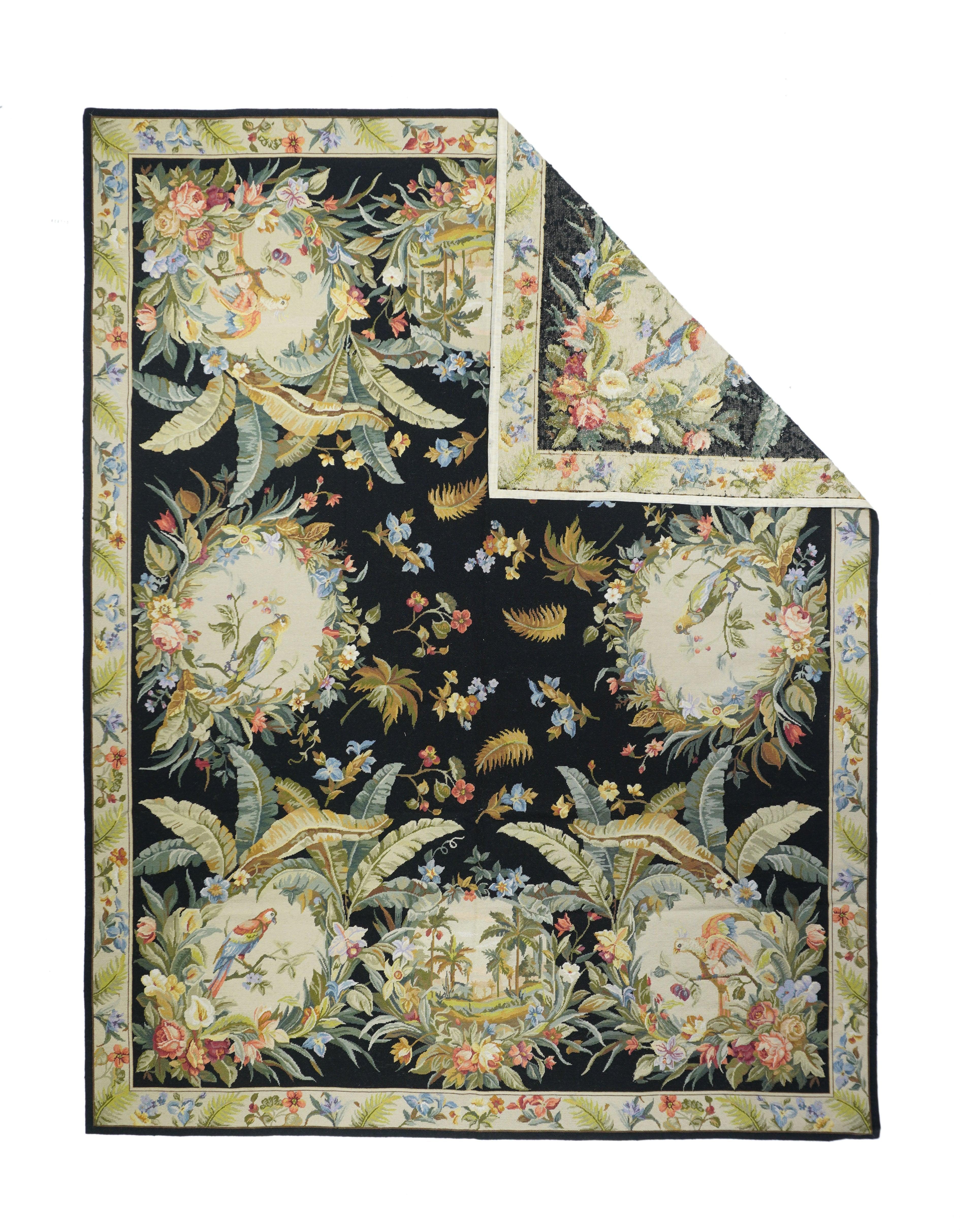 Tappeto francese design Aubusson 7'11'' x 10'1''. Il campo quasi nero esplode con sei grandi tondi di fiori tropicali e foglie giganti che racchiudono uccelli colorati; e due riserve più piccole che racchiudono vignette di paesaggi tropicali. Le