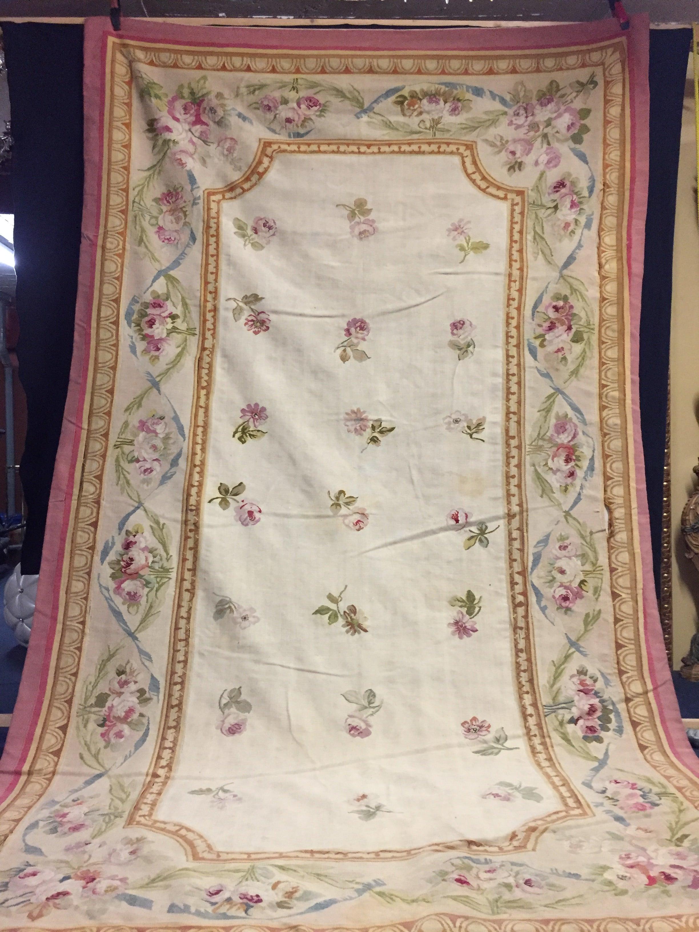 Beautiful flat handwoven carpet made of French Aubusson with an elegant design, subtle colors and delicate floral motifs. Rich and soft light background with pink flowers and ornaments, decorated with a centered medallion of flowers with flowers.