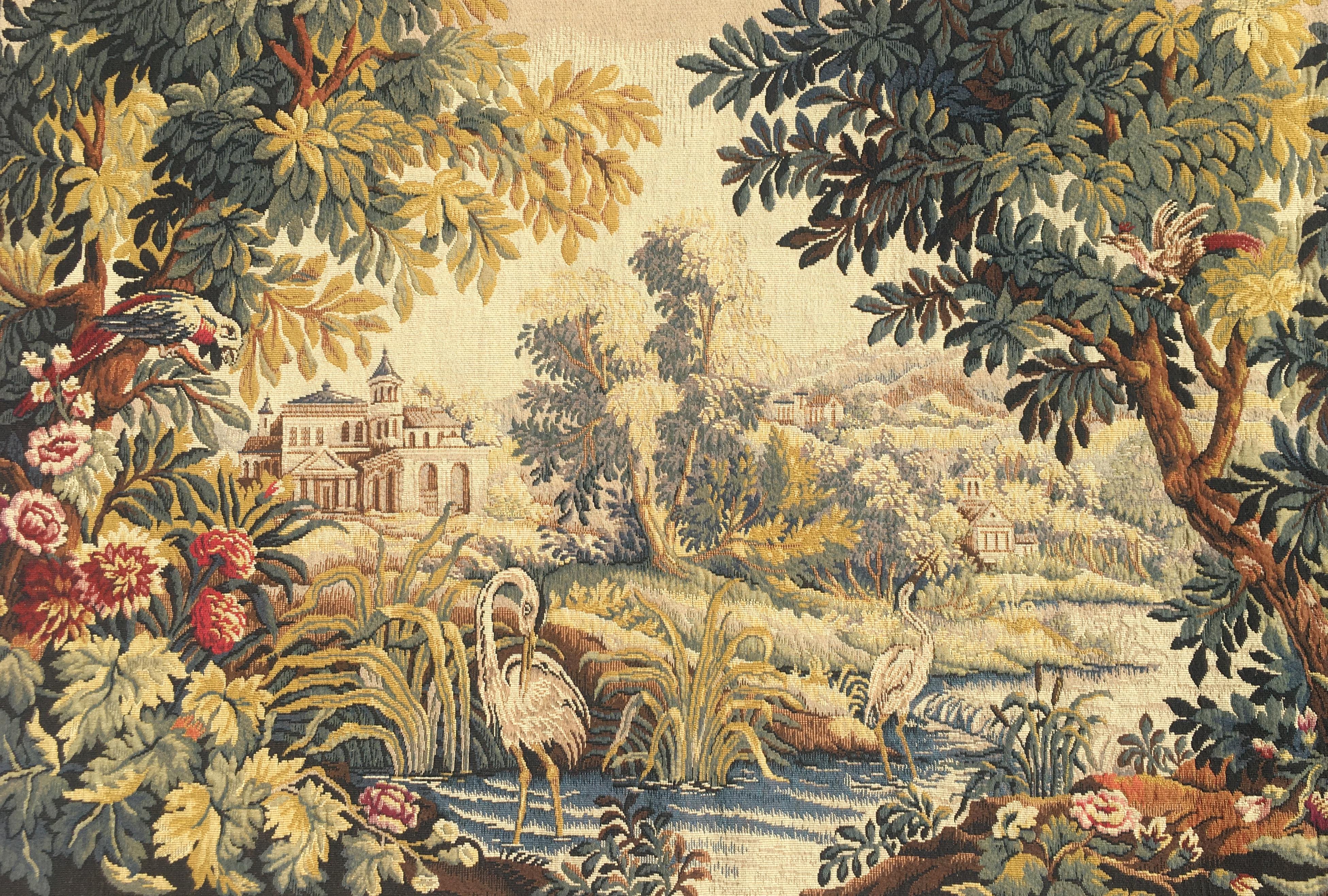 This colorful handmade tapestry was woven in Flandres de Halluin, France in the 20th century. The beautiful wall hanging depicts a traditional Aubusson scene. The lush, green composition features castles, domaines, a river, ducks and foliage.