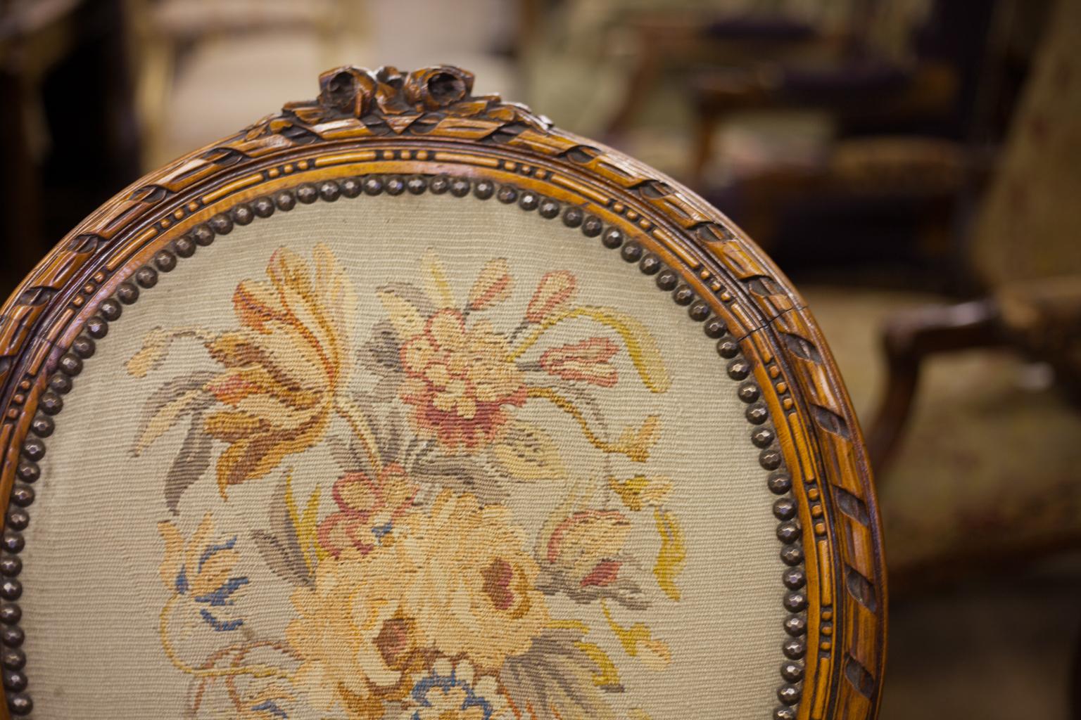 French Aubusson tapestry armchair, with faceted brass stud work surrounding the tapestries, handsomely carved scroll work and floral crest. It has cabriole legs and fluted acanthus carved arms and arm supports.