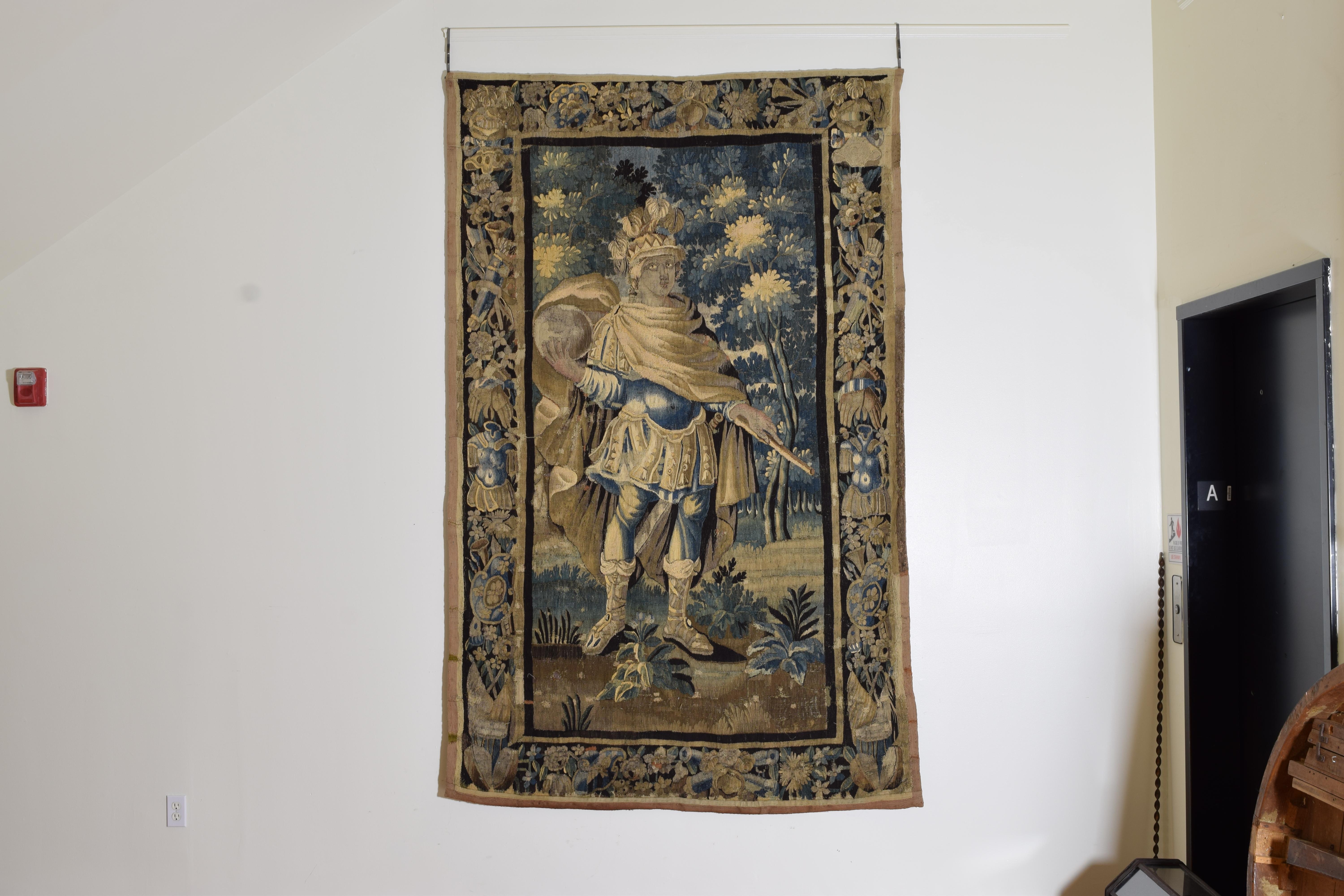 The tapestry depicting King Solomon as a warrior king standing with a globe and staff in his hands framed within a border of armaments, flora, and fauna, the tapestry recently restored and now with a new backing and hanging sleeve