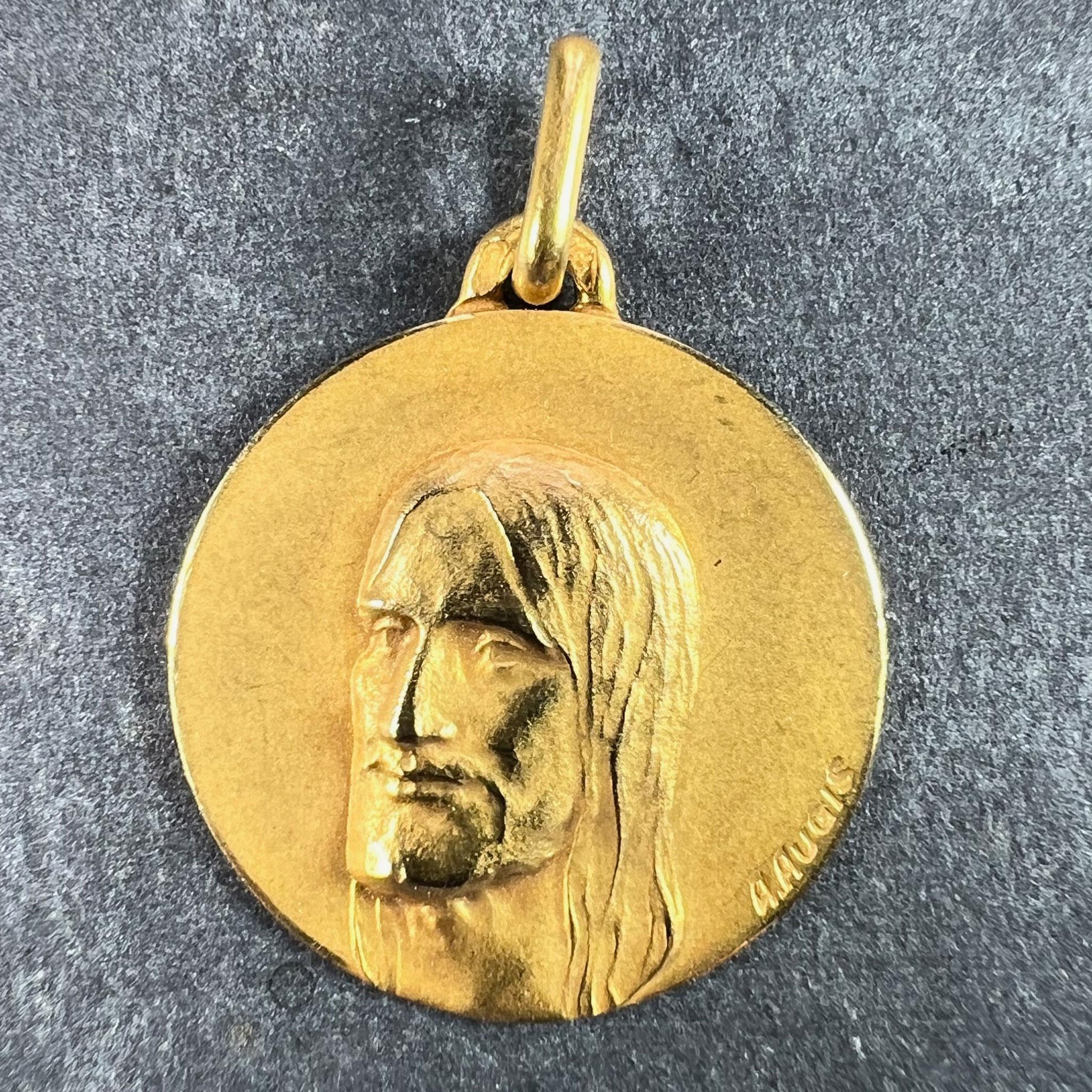 A French 18 karat (18K) yellow gold charm pendant designed as a round medal depicting Jesus Christ in three quarters profile. Signed Augis, stamped with the eagle’s head for 18 karat gold and French manufacture, along with maker's mark for Augis,
