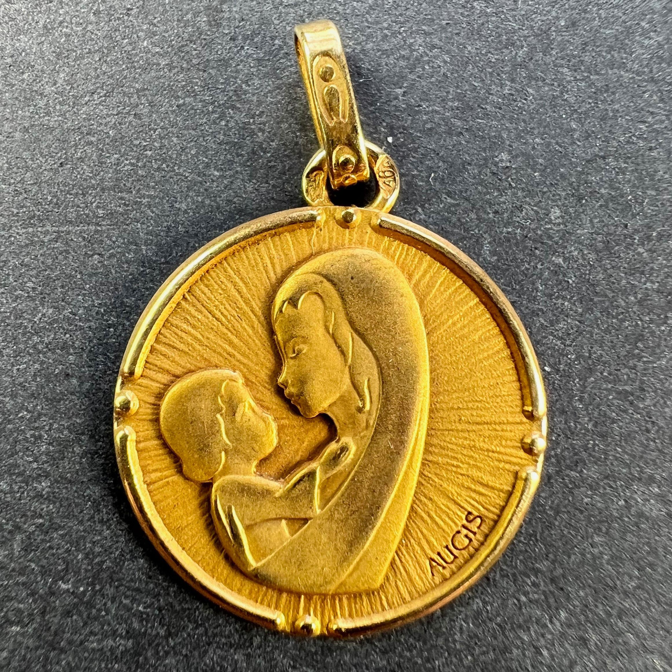 Ein französischer Anhänger aus 18 Karat (18K) Gelbgold in Form einer Medaille mit der Darstellung der Madonna mit Kind, signiert von Augis. Gestempelt mit der Adlerkopfmarke für 18 Karat Gold und französische Herstellung sowie der Herstellermarke