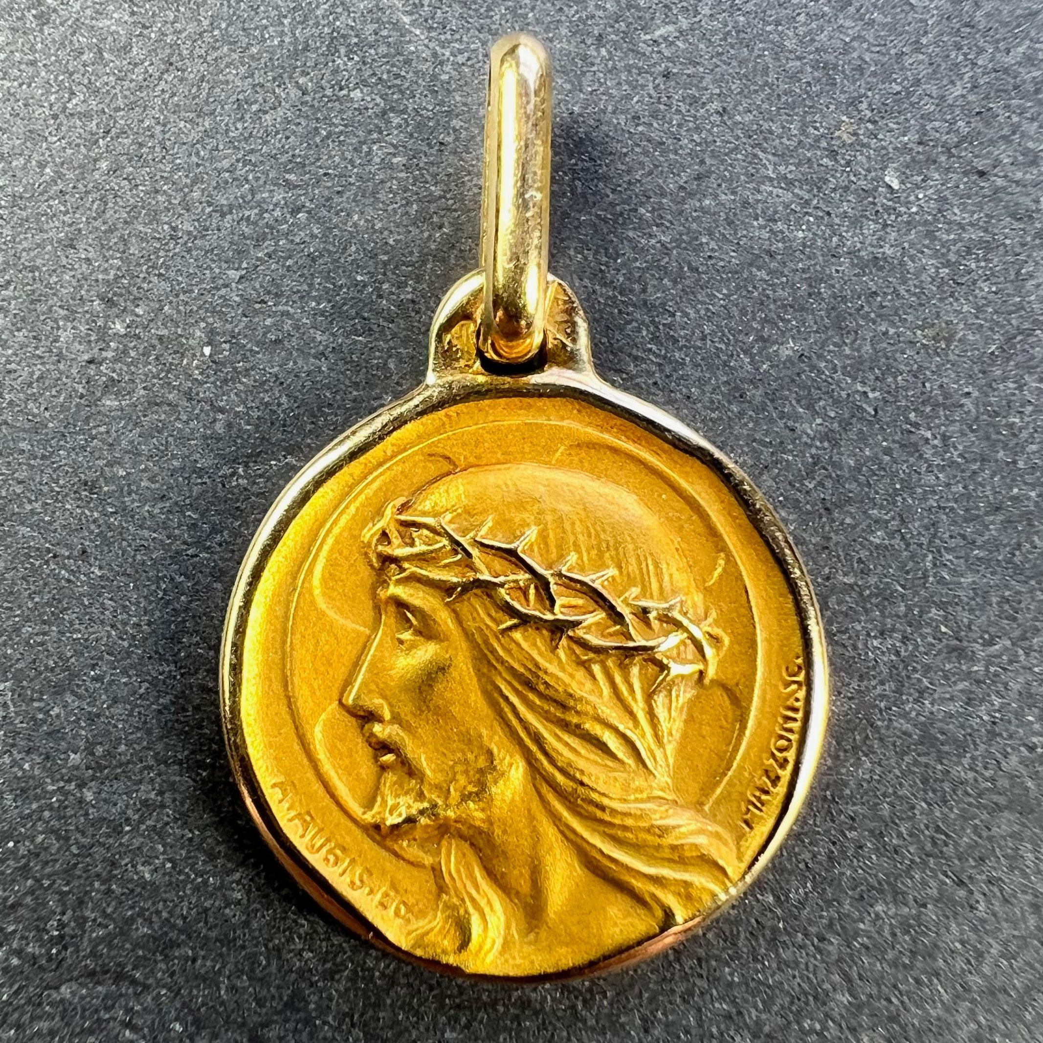 A French 18 karat (18K) yellow gold charm pendant designed as a round medal depicting the profile of Jesus Christ wearing the Crown of Thorns, in front of a halo shaped like a cross. Signed A.Augis and Mazzoni. Stamped with the eagle’s head for 18