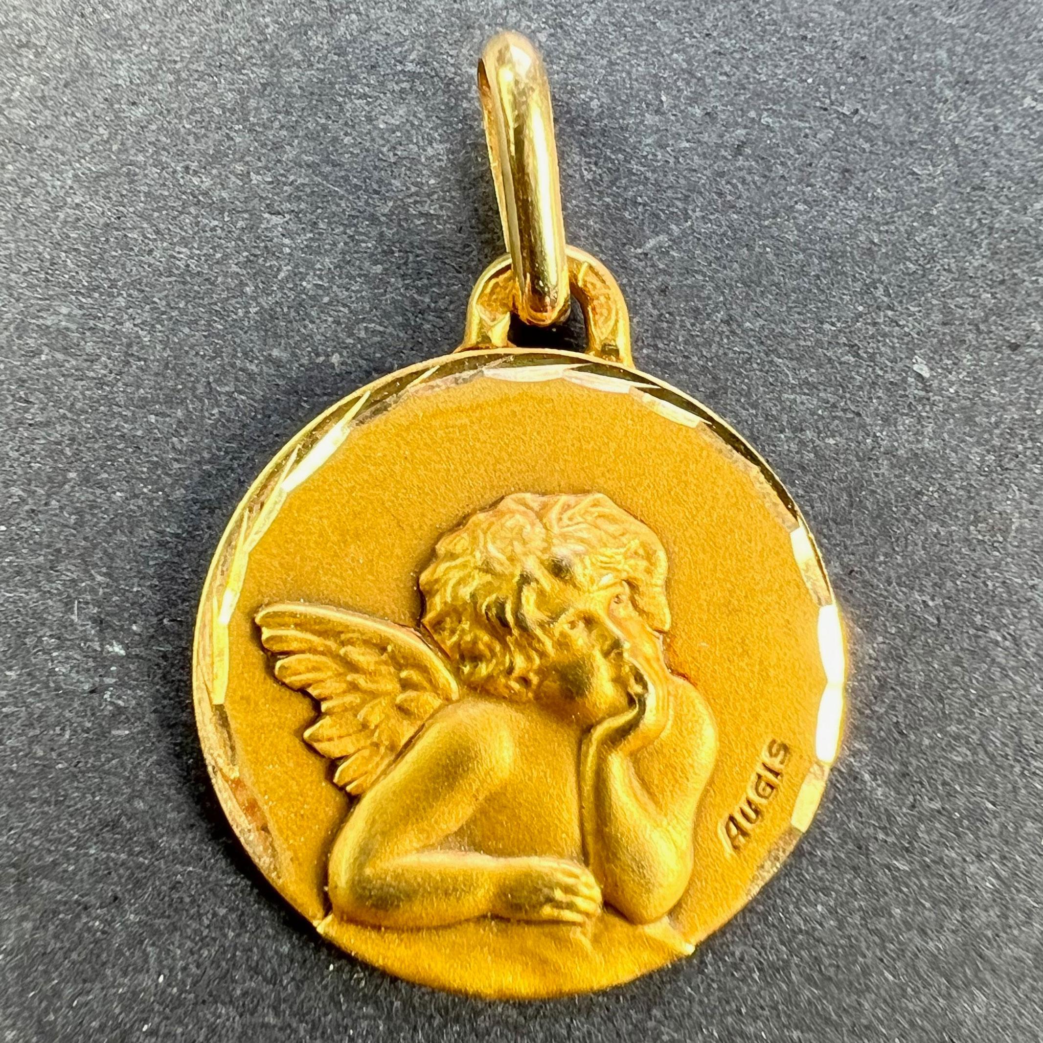 A French 18 karat (18K) yellow gold charm pendant designed as a round medal depicting Raphael’s cherub. Signed Augis. Stamped with the eagle mark for 18 karat gold and French manufacture with an unknown maker's mark. The reverse marked A for