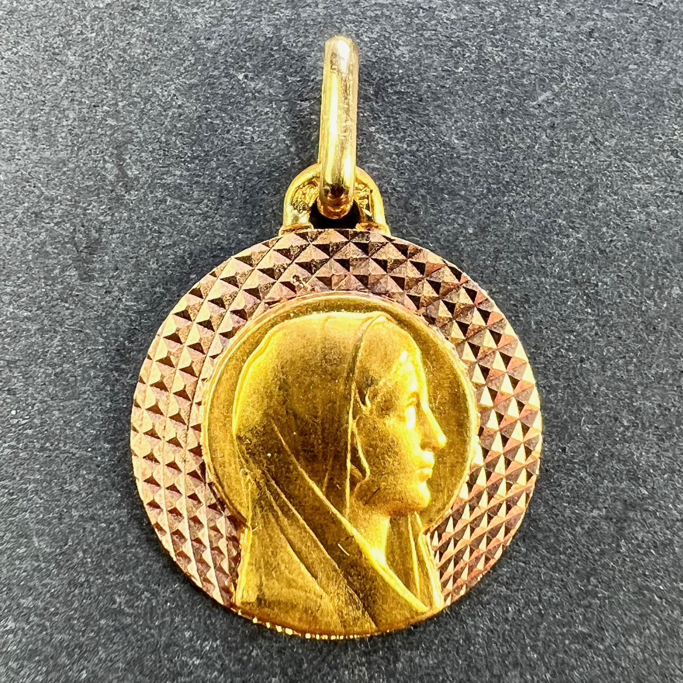 A French 18 karat (18K) yellow gold religious charm pendant designed as a medal depicting the Virgin Mary with a halo against a radiating diamond cut rose gold background. Stamped with the eagle's head mark for 18 karat gold and French manufacture