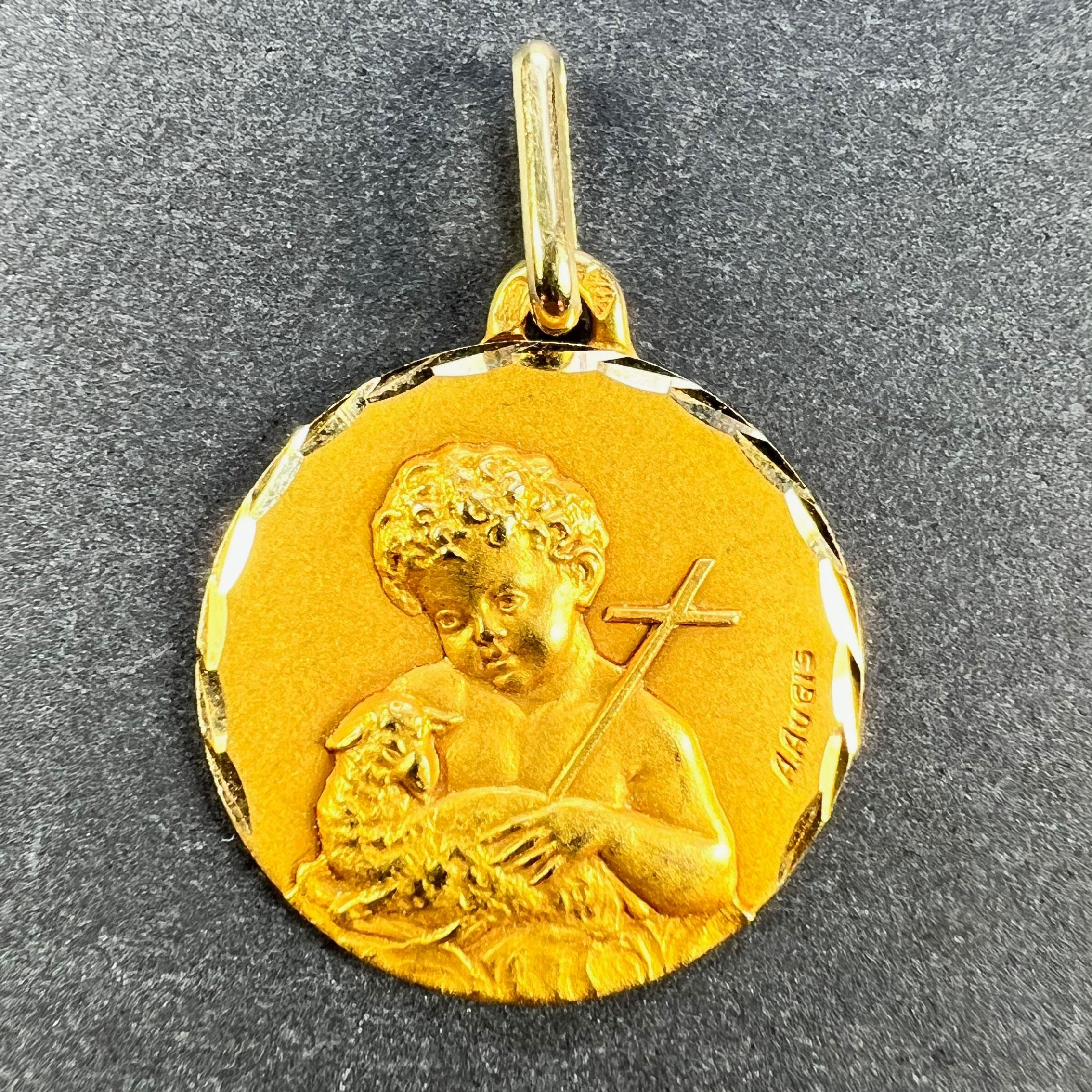 A French 18 karat (18K) yellow gold charm pendant designed as a medal representing Saint John the Baptist as a child with a cross and a sheep. Signed A. Augis, stamped with the eagle's head for French manufacture and 18 karat gold with Augis's