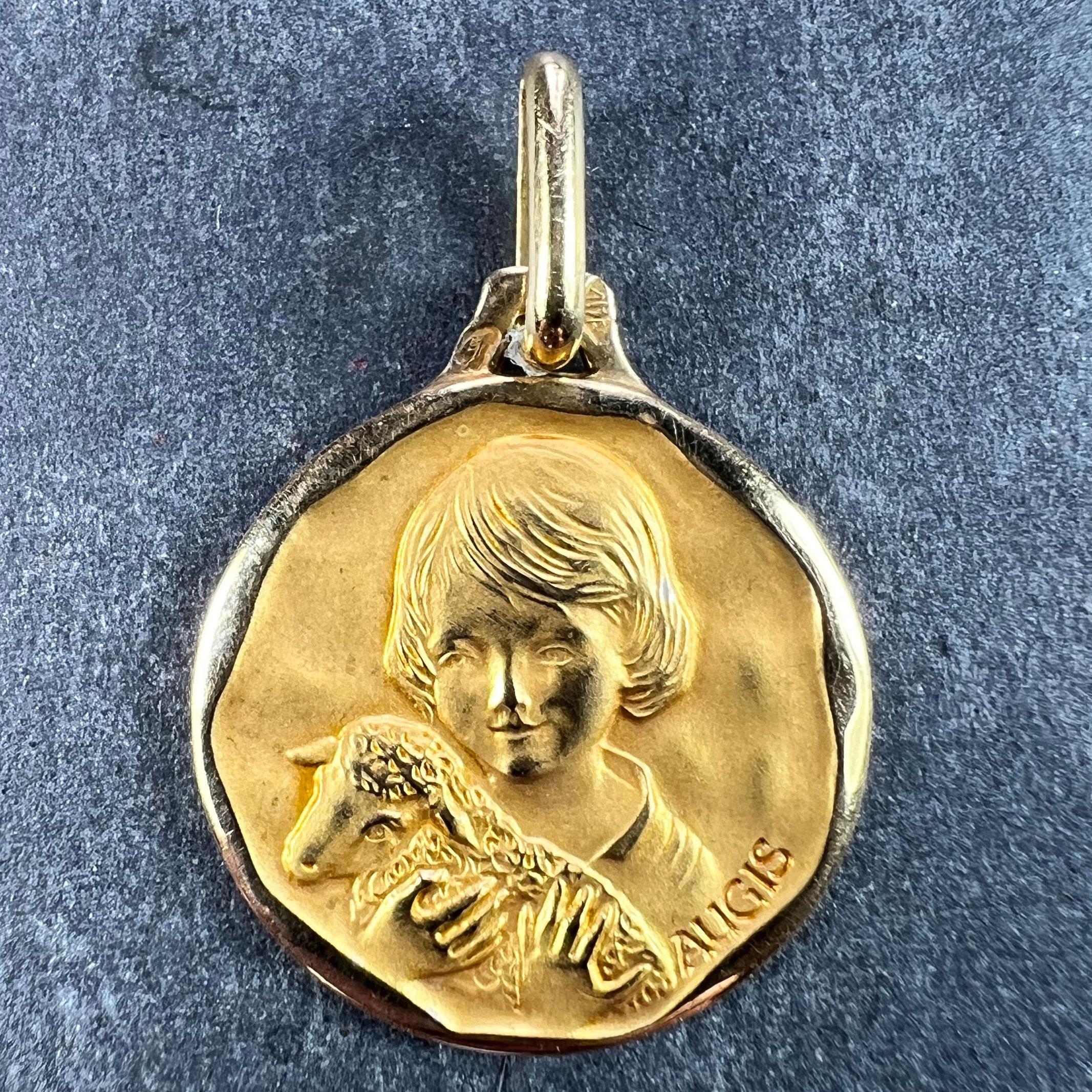 A French 18 karat (18K) yellow gold charm pendant designed as a medal representing Saint John the Baptist as a child with a lamb. Signed  Augis, stamped with the eagle's head for French manufacture and 18 karat gold with Augis's maker’s mark.