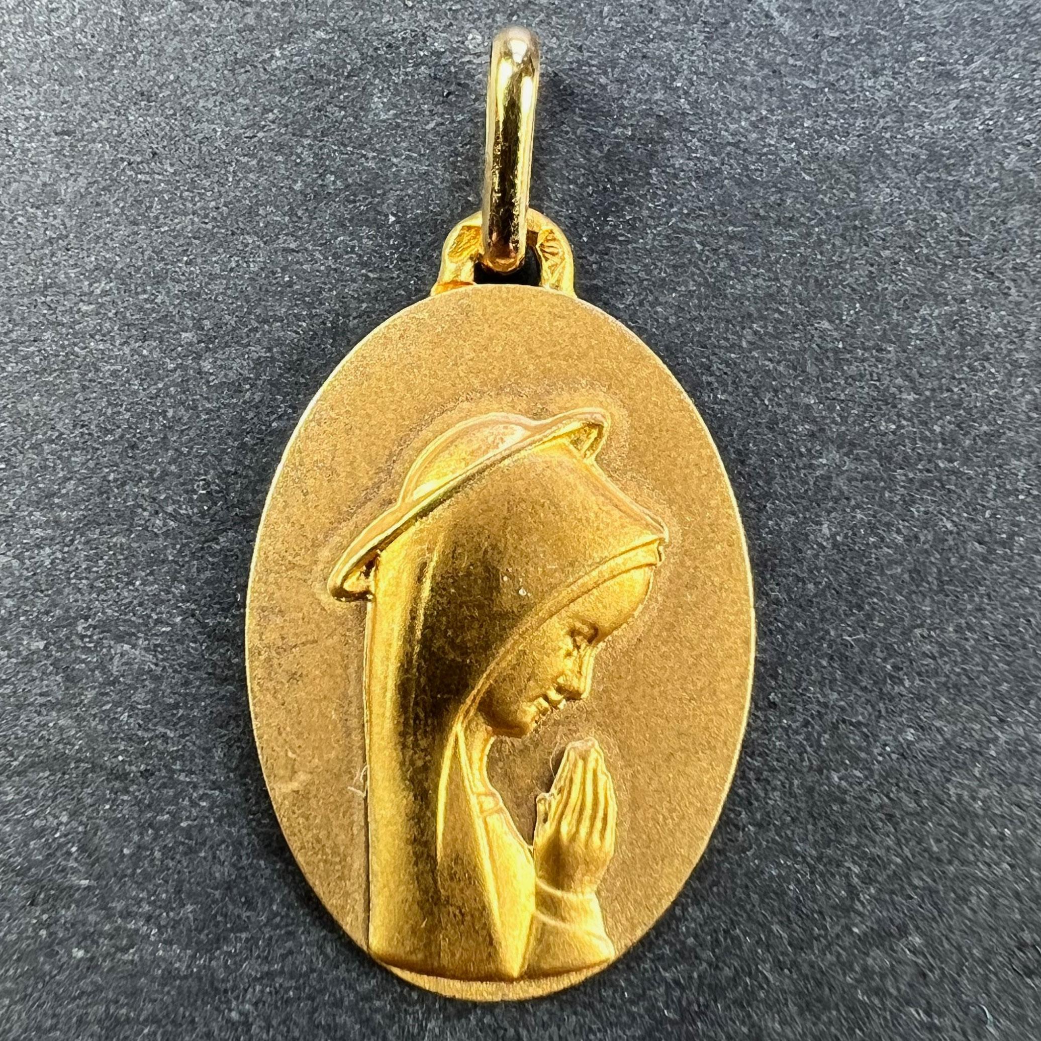 A French 18 karat (18K) yellow gold pendant designed as a round medal depicting the Virgin Mary within a halo. Marked with an A for Augis to the reverse of the pendant loop. Stamped with the eagle’s head for French manufacture and 18 karat gold,