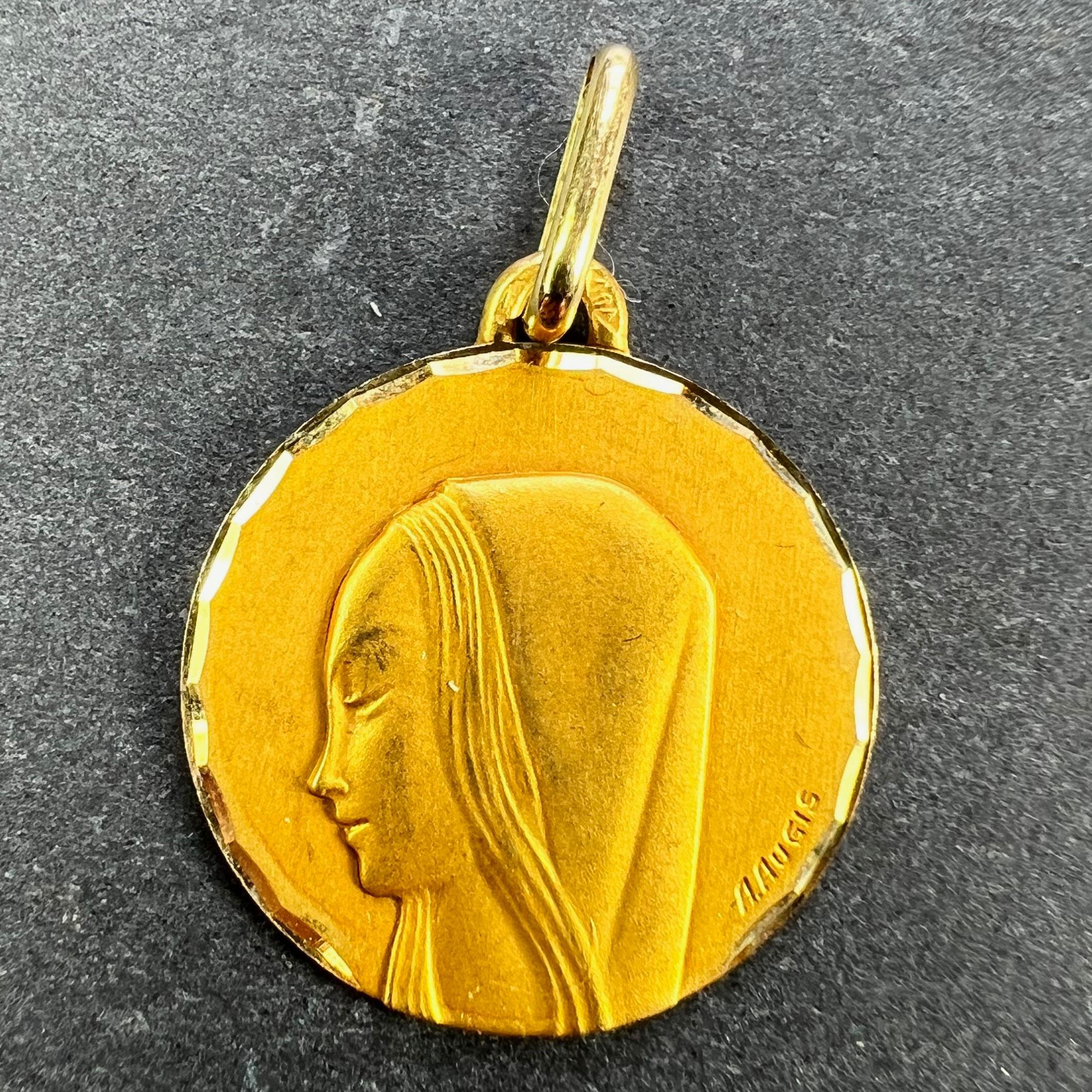 A French 18 karat (18K) yellow gold pendant designed as a round medal depicting the Virgin Mary within a faceted scalloped frame. Signed A.Augis. Marked with an A for Augis to the reverse of the pendant loop. Stamped with the eagle’s head for French