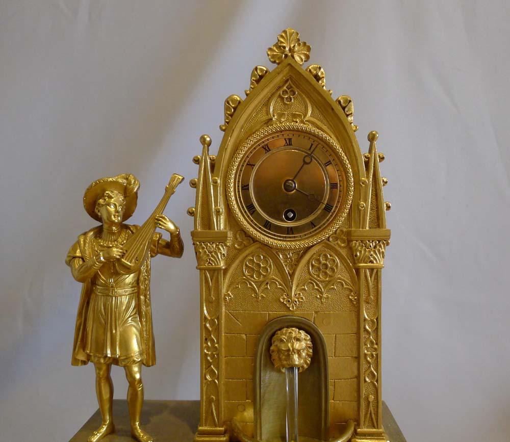 Antique French romantic period ormolu cased automaton fountain clock with Gothic architectural tower and lion's head fountain spout. A troubadour stands on the left hand side of the clock playing a lute. The base decorated with frieze of Gothic