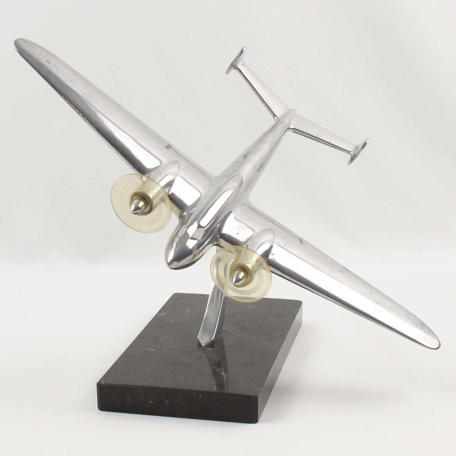 Elegant midcentury French aluminum airplane model, mounted on a marble plinth. This nice sculptural model airplane is made with cast aluminum and has two original Lucite propellers. Standing on a geometric marble plinth in black and white swirled