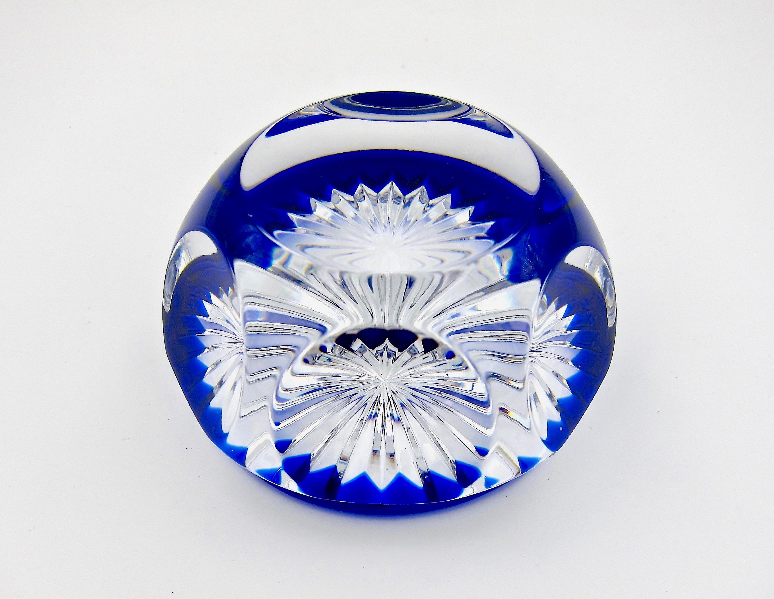 A multifaceted Baccarat art glass paperweight made in France during the company's Modern Period, 1953-2001. The vintage clear crystal weight has six and one facets with cobalt-blue glass encircling a foot decorated with a 24-point star-cut base.