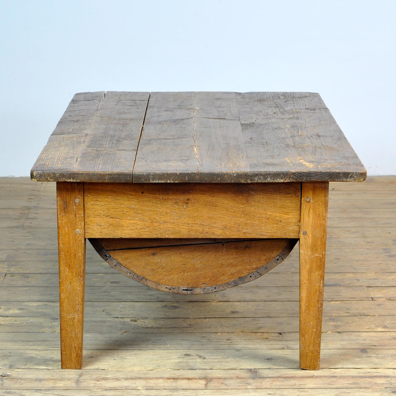 Bakers table from France, produced around 1930 with a nice round storage space under the top. The table is made of an oak base with a pine top. The legs of the table have been shortened to coffee table height.