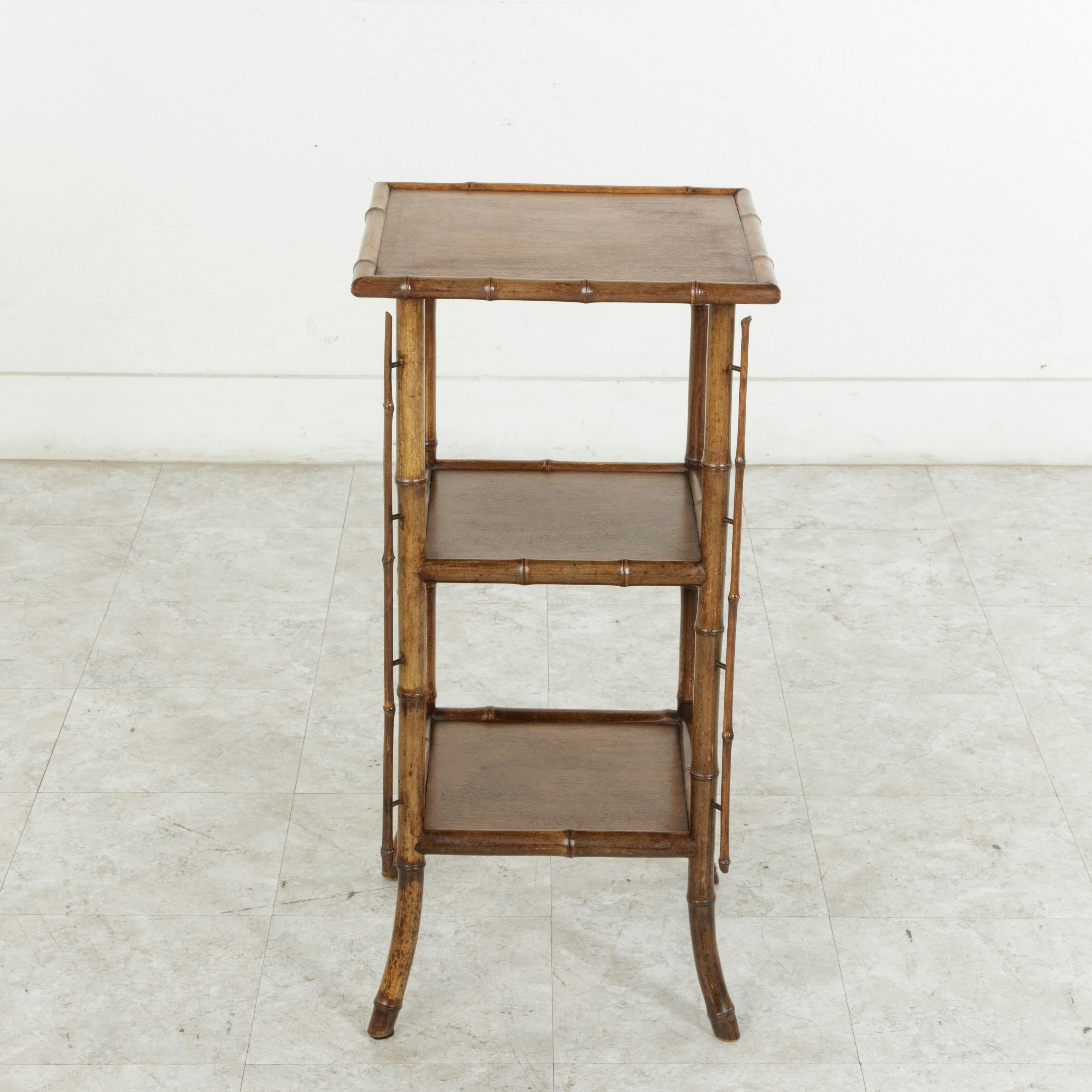 This French fern stand from the turn of the twentieth century features a construction of bamboo with three mahogany shelves. The four legs gently flair out at the bottom, and bamboo shoots are offset from the legs giving the piece a contemporary