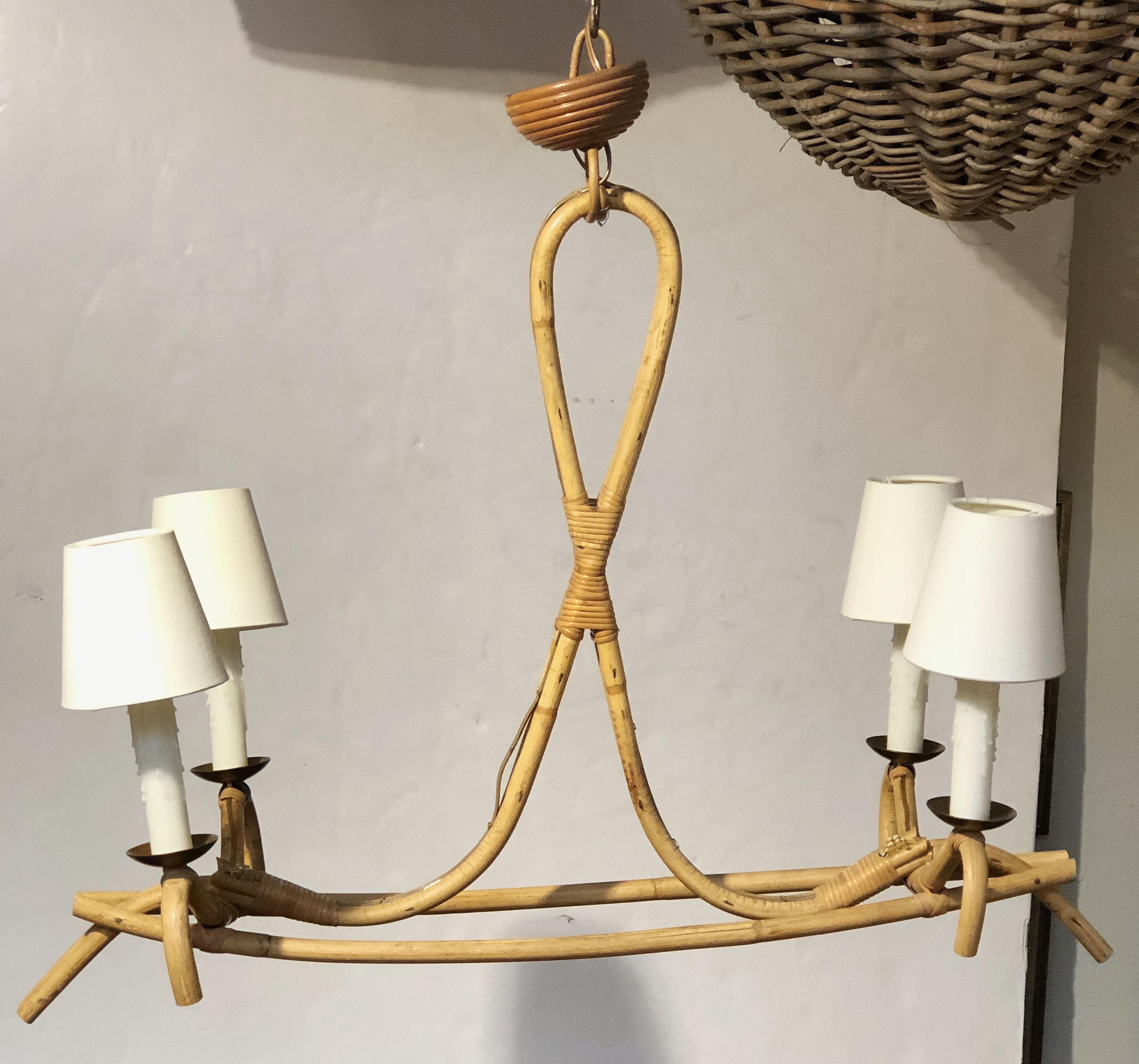 A fine French bamboo hanging fixture from the mid-20th century, featuring four lights, each light with brass bobeche and optional shade, on a stylish bamboo and rattan support, attributed to the famed French designer, Louis Sognot.

Attributed to