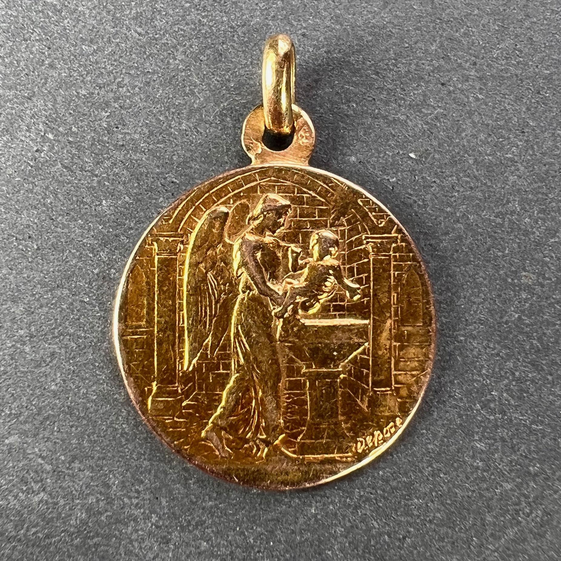 An 18 karat (18K) yellow gold charm pendant depicting an angel holding an infant over a font for baptism. Engraved to the reverse ‘SUZANNE’ and the date 26 Aout 1900. Stamped with the eagle mark for 18 karat gold and French manufacture and marked