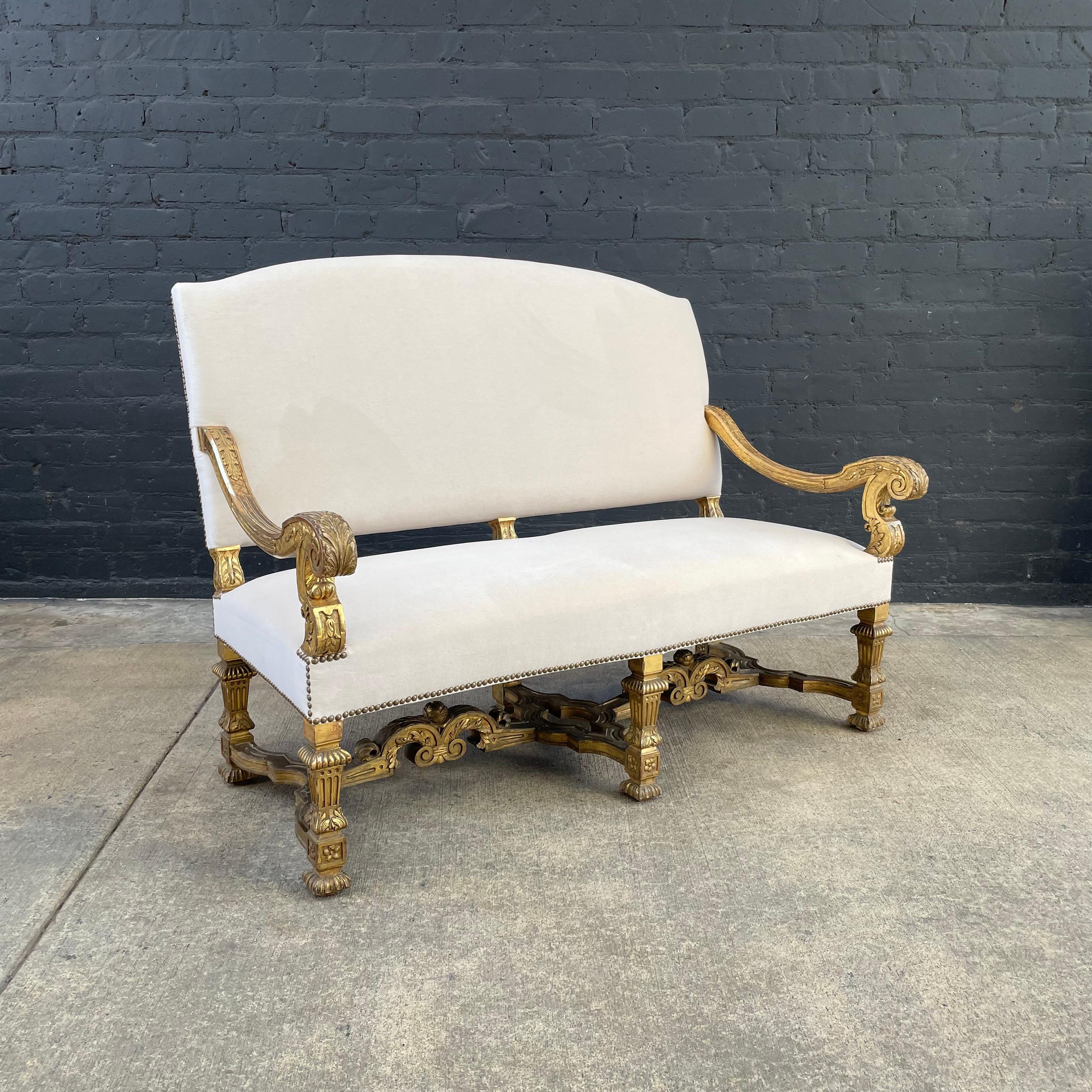 Impactful, French Louis XIV Baroque-style carved giltwood settee, newly upholstered in mohair and finished with an antiqued brass nail head trim. 

This settee’s detailed carved Baroque styling is beautifully highlighted by it’s original water-gild