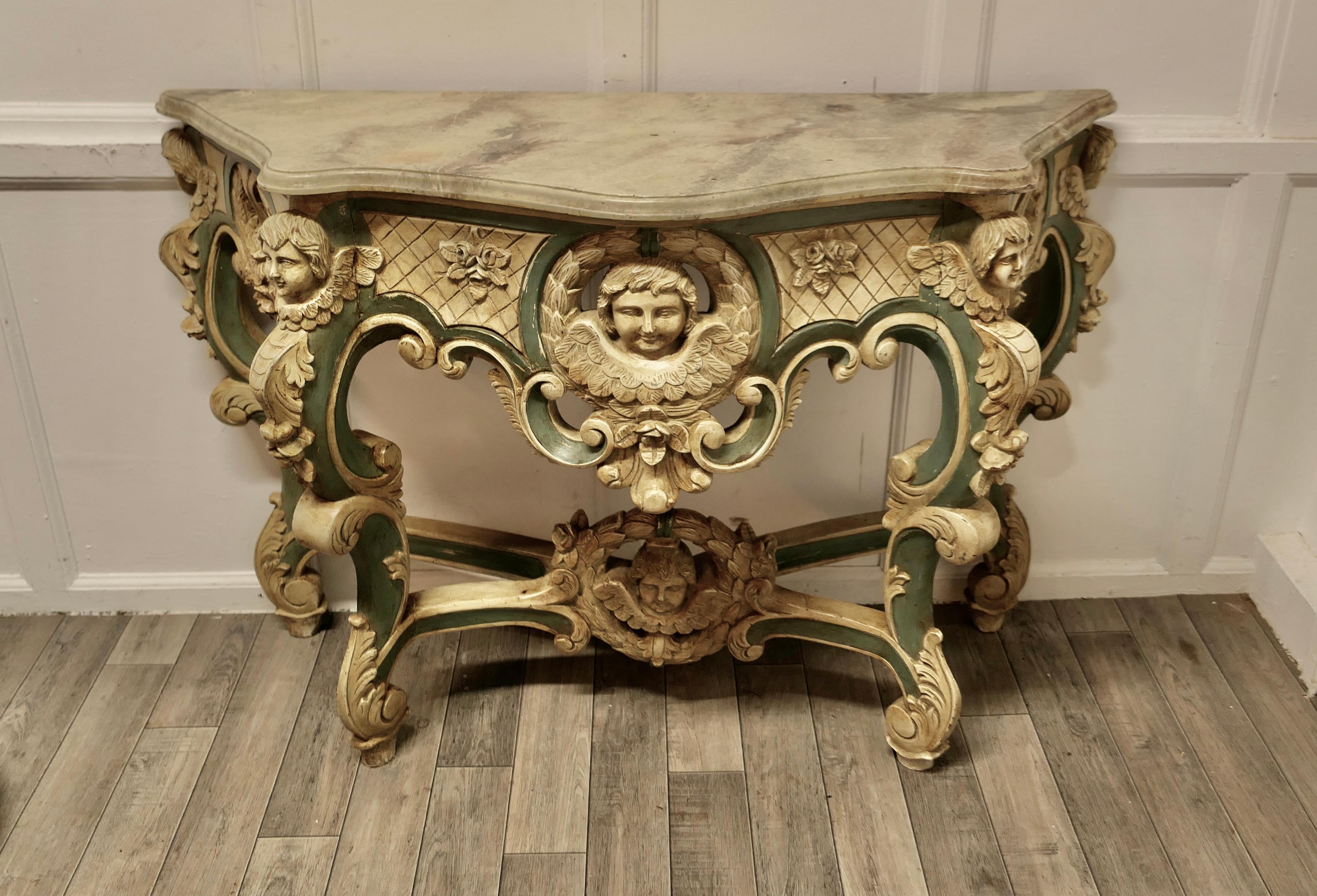 French Baroque console table, carved and painted with the faces of angels


This is a very attractive piece, the table is hand carved with bold figural, scroll and shell decoration, it has a scalloped bow fronted shape with a moulded edge to the