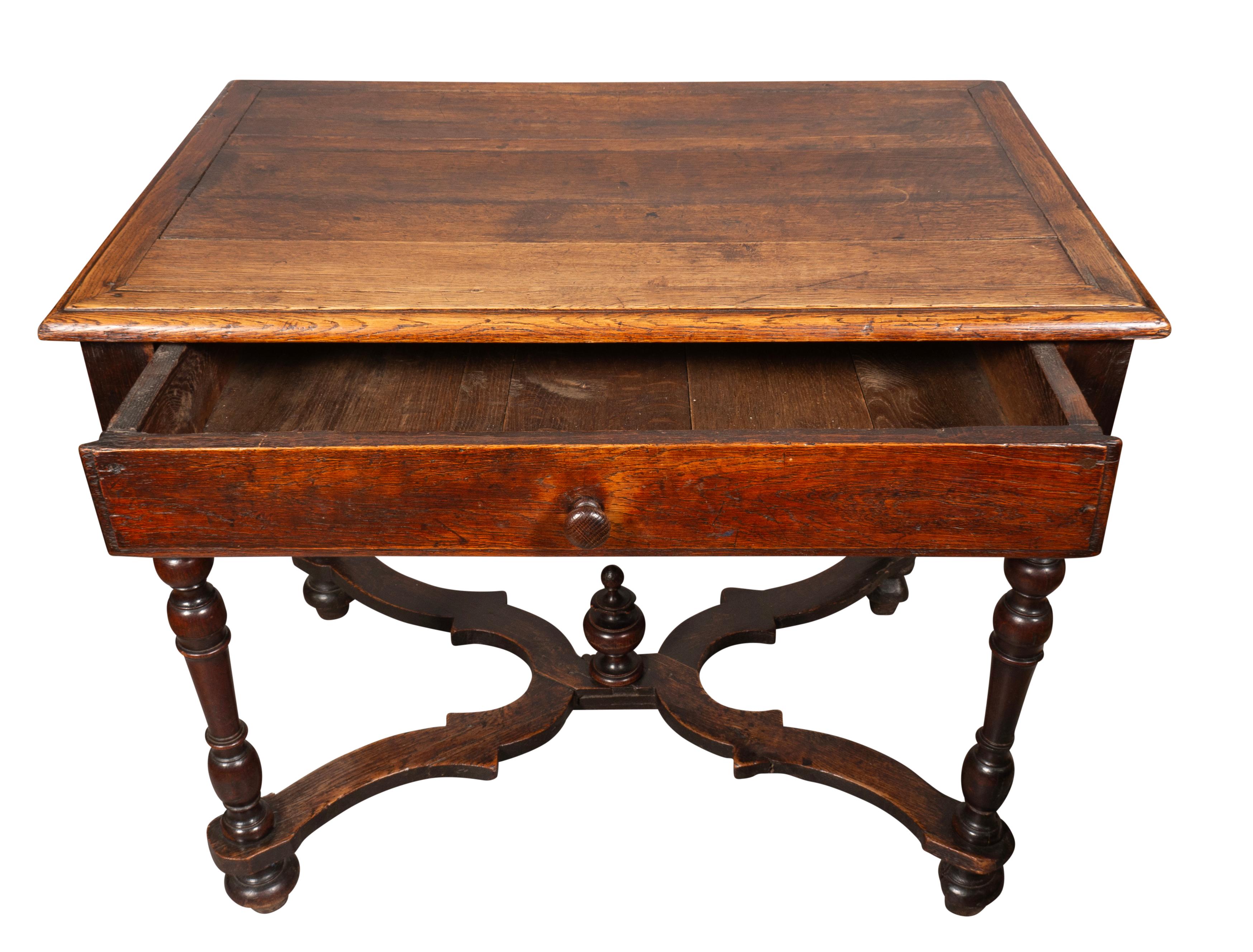 Rectangular top over a single drawer with scalloped apron. Raised on turned legs joined by flat X form stretchers with central finial.