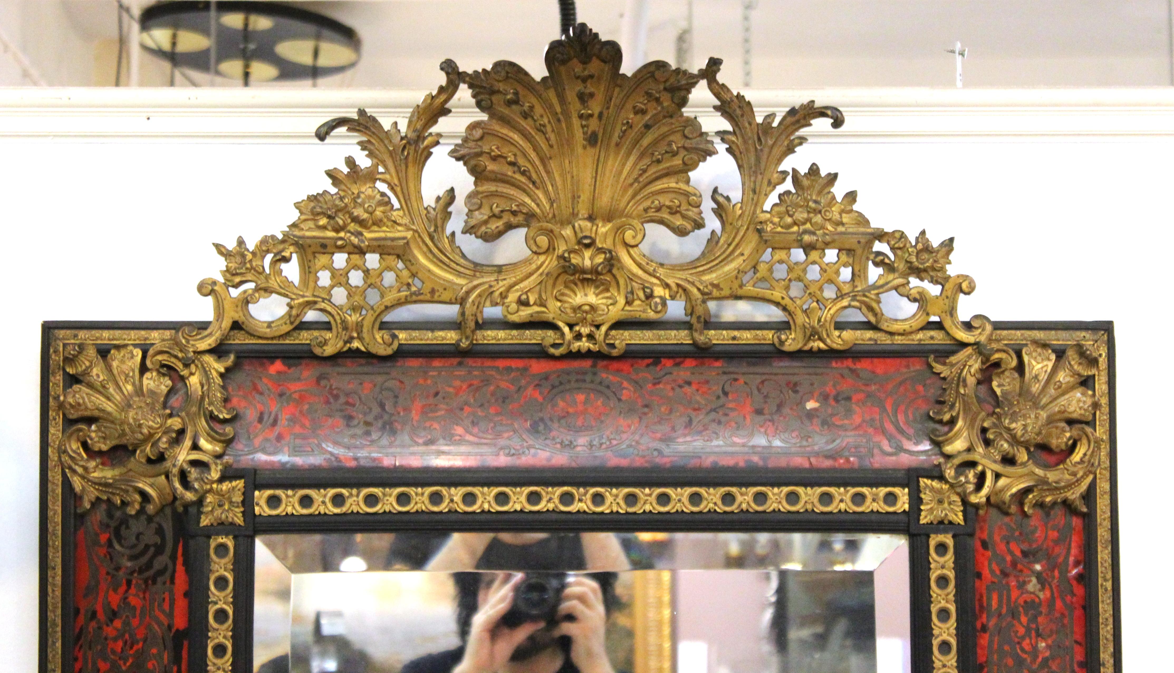 French Baroque Revival wall mirror with pediment and elaborate faux tortoiseshell band decor with Boulle style metal inlay. The piece was likely made during the late 20th century and is in great antique condition with age-appropriate wear and some