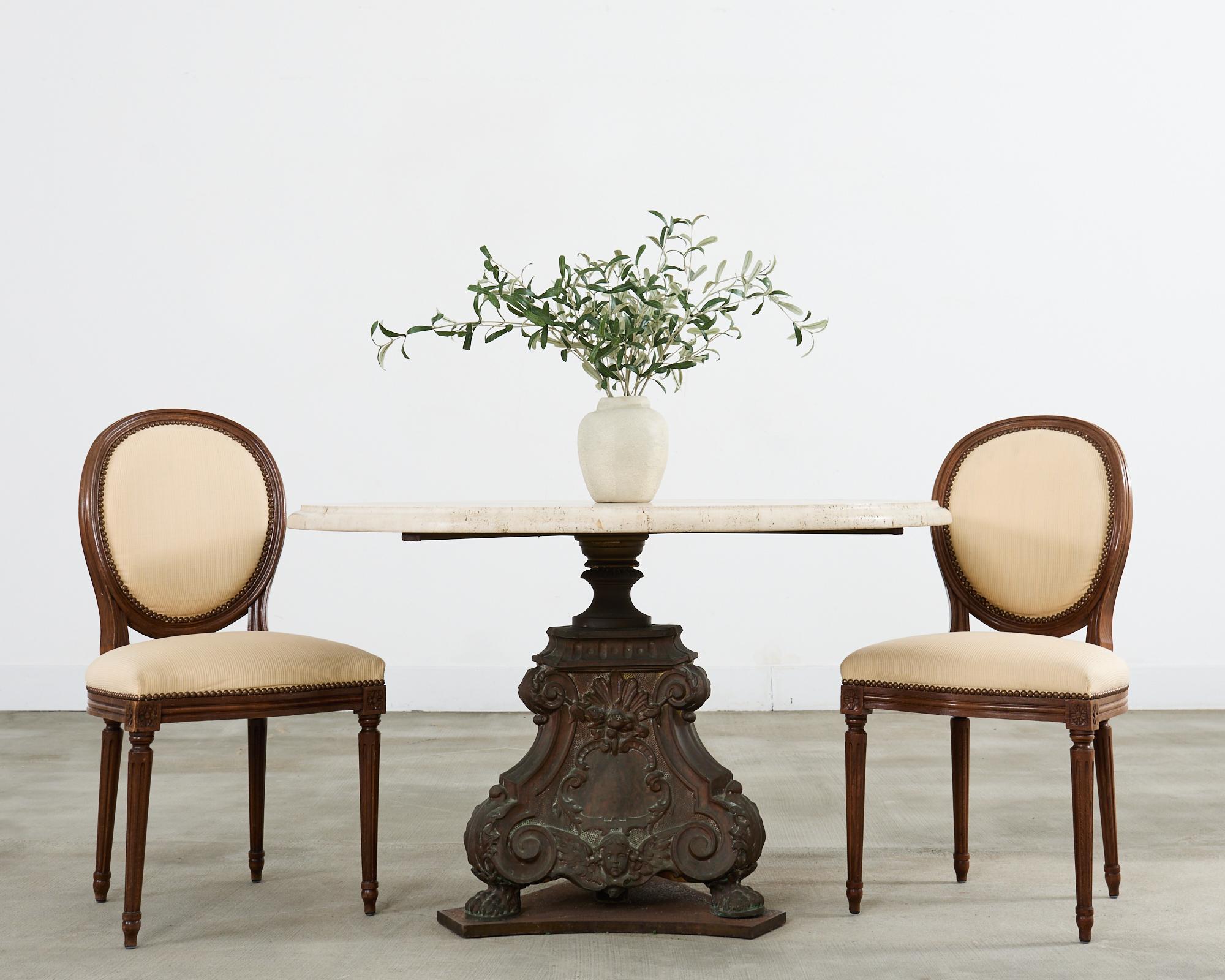 Impressionnante table à manger ou table centrale de jardin à piédestal français, avec une base en bronze patiné surmontée d'une épaisse plaque de travertin italien. Le plateau rond mesure 1,5 pouce d'épaisseur avec un bord biseauté en forme d'ogee.