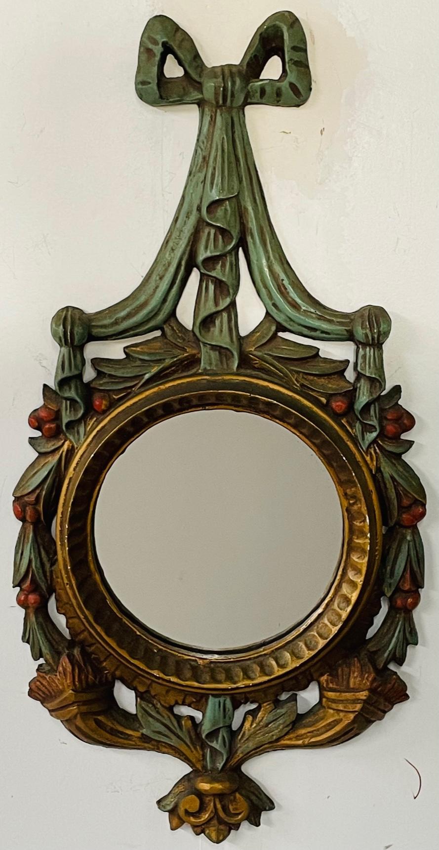 An exquisite French Baroque style bullseye wall mirror. The circular shape antique mirror is finely wood carved and hand painted in Green and gilt tone. The mirror features a large bow / ribbon crowning the mirror and decorated with leaves motif