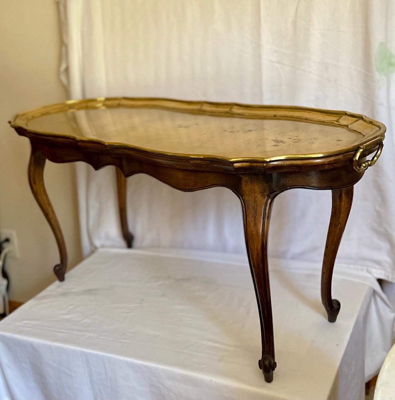 French Baroque Style German brass tray top yale burge coffee table.

Elegant French Country Baroque style walnut coffee table with solid brass removable two handled tray top. The well crafted wood table is raised on four cabriolet legs with a