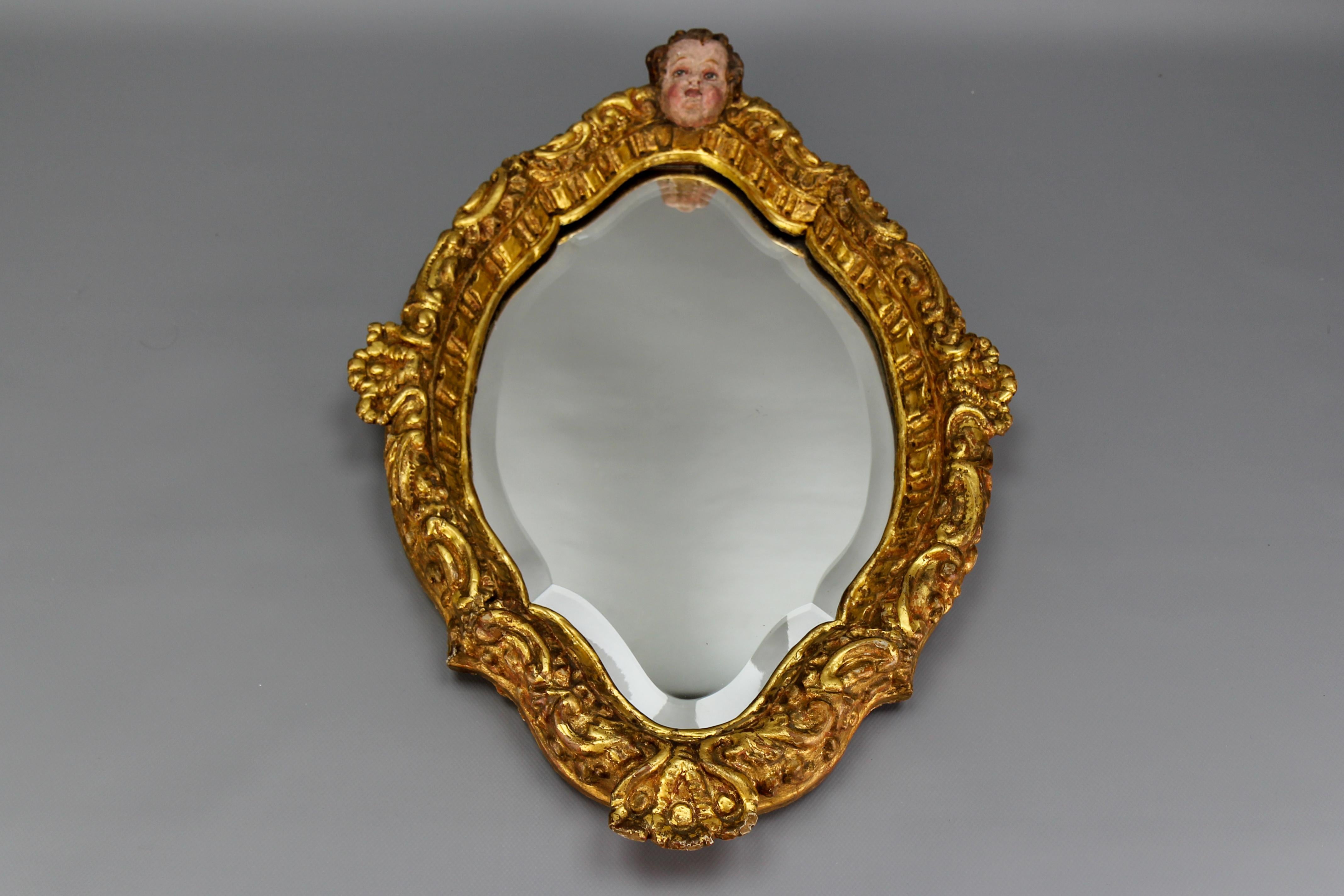 French Baroque style giltwood wall mirror with a cherub decoration.
An adorable wall mirror with a gilt wood frame richly decorated with stylized leaves and a cherub head on the top of the mirror frame. The wall mirror has a slightly faceted