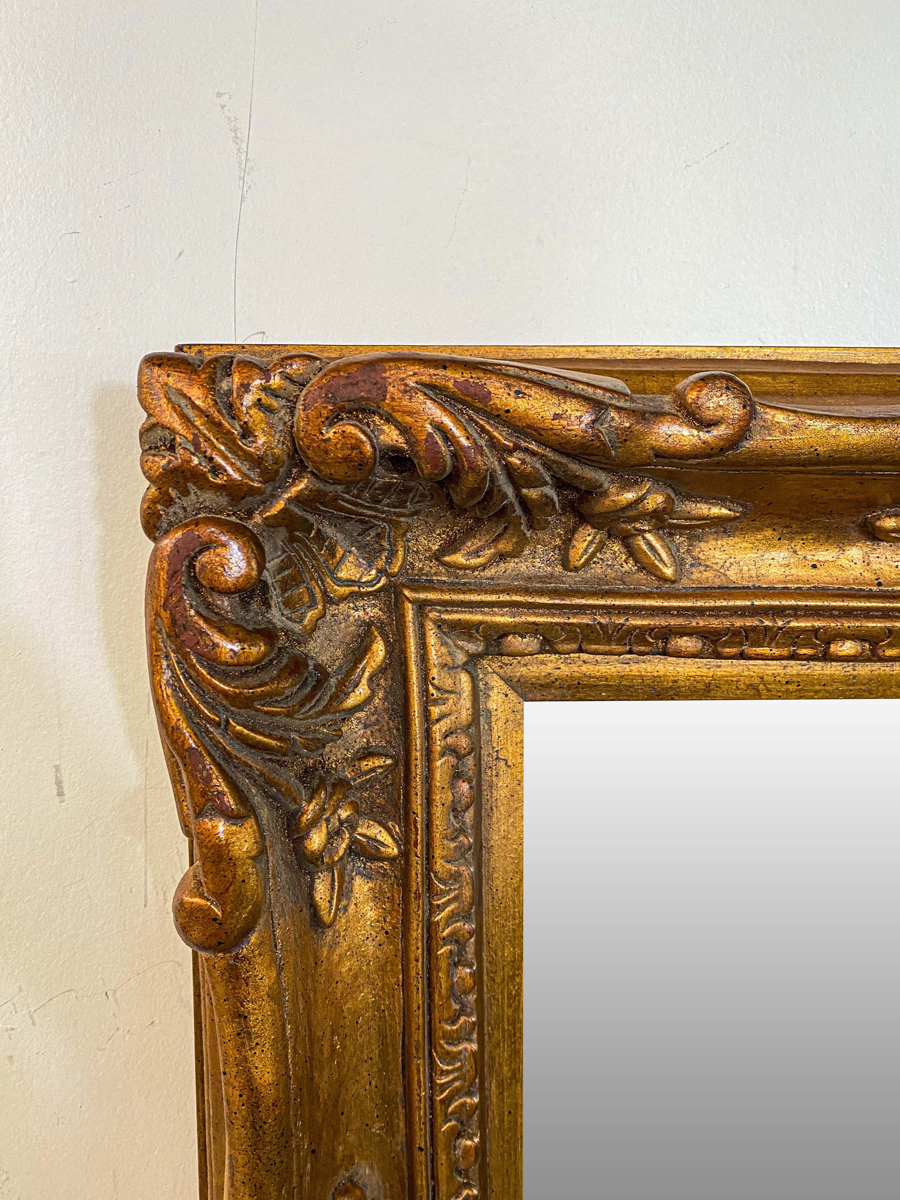 Un miroir rectangulaire de style baroque français, élégant et de grande classe. Finement sculpté et présentant des motifs complexes de fleurs, d'acanthes et de feuilles, le miroir est fabriqué en bois doré et sa taille moyenne est parfaite pour