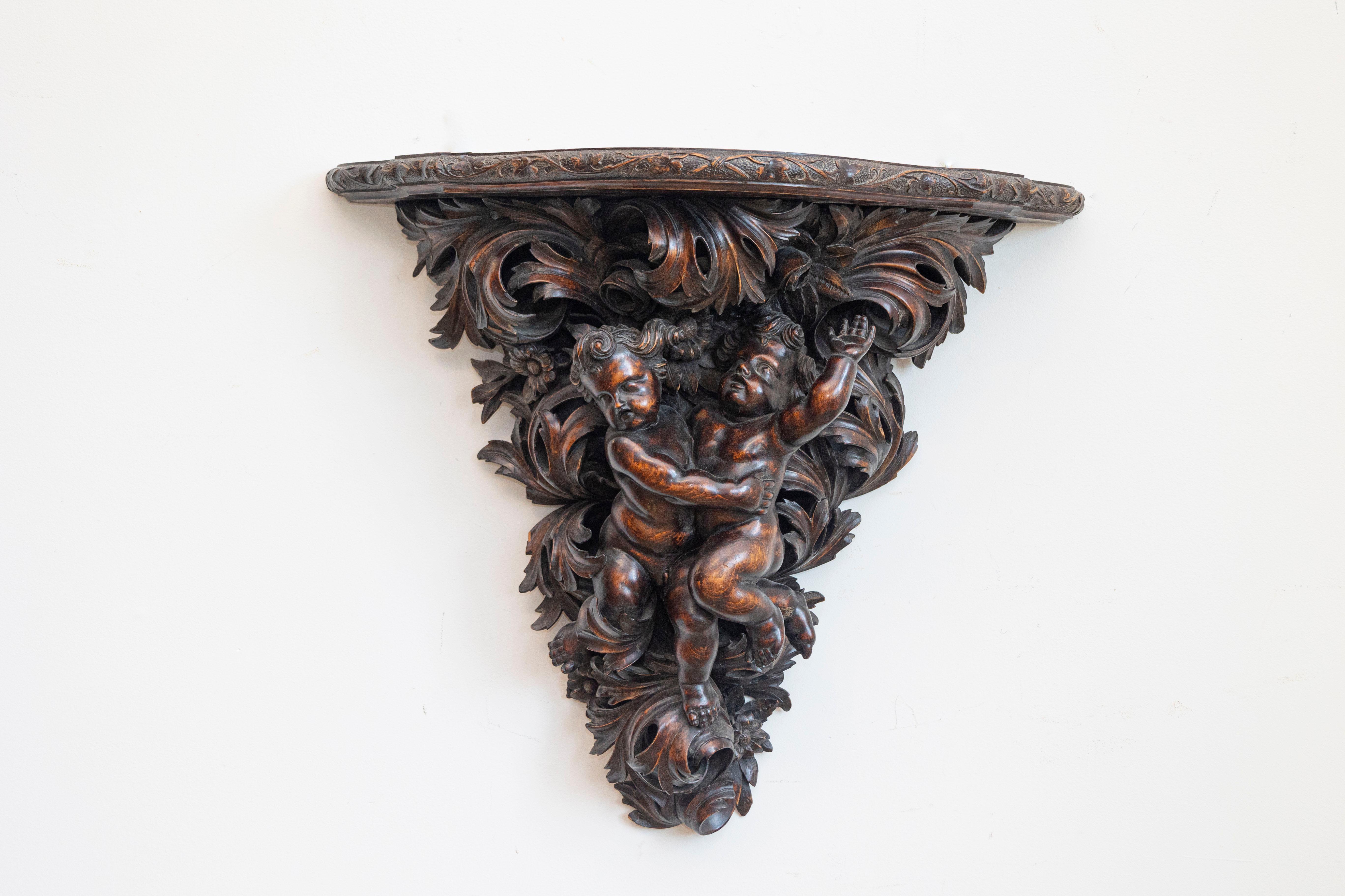 A Baroque style French walnut bracket with hand-carved putti, circa 1800. Born during the tumultuous years of the early 19th century, this French bracket features a semi-circular shaped top, adorned with an ivy carved molding. It it the base,