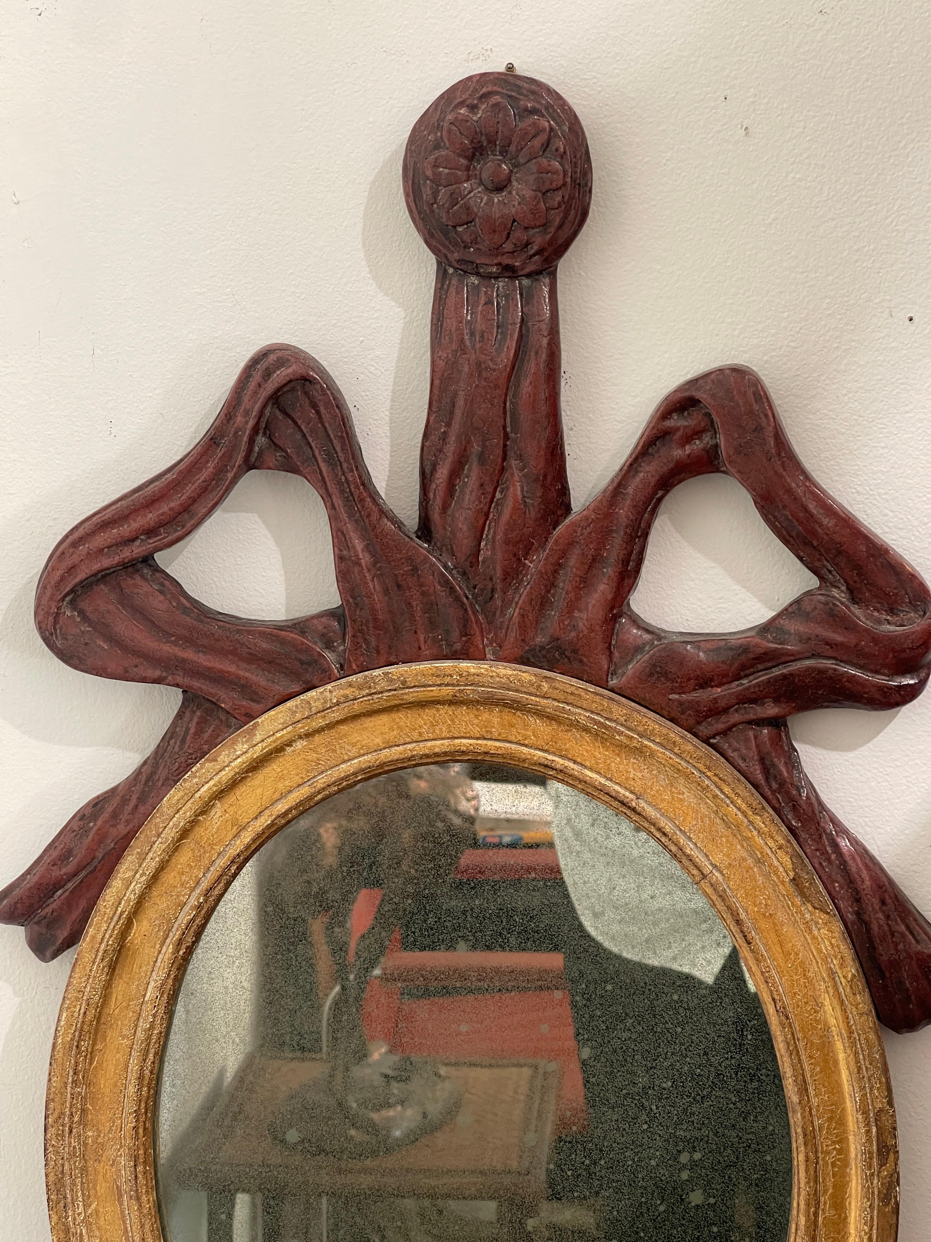 Specchio da parete ovale in stile barocco francese. 
Lo specchio presenta un grande fiocco e un nastro che incorona lo specchio dorato. 
Un doppio portacandele in ferro nella parte anteriore.
Questo specchio di charme ha un'ottima qualità  lo stile,