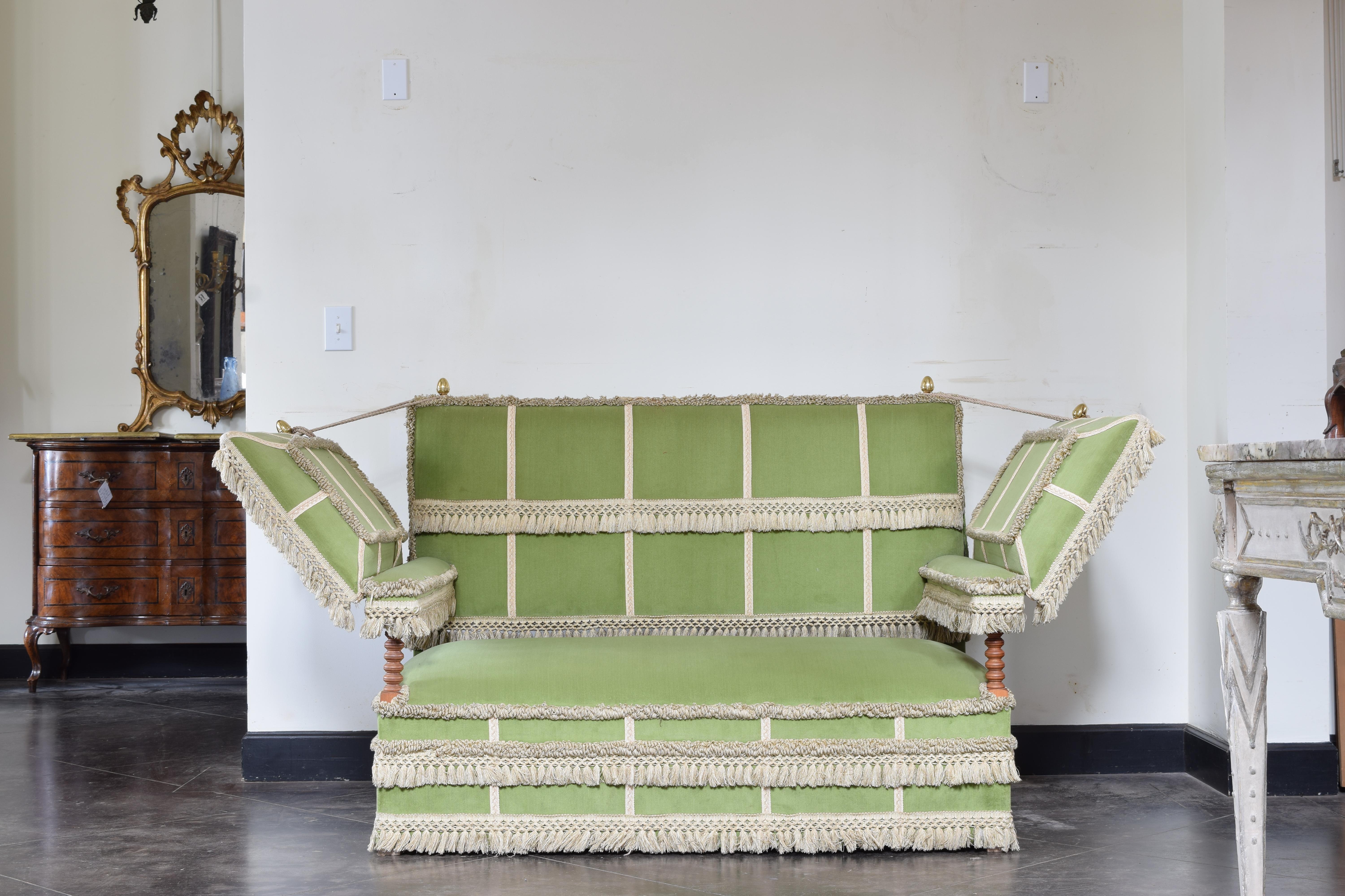 Upholstered in green velvet with applied embroidered tape/trim with matching braid and fringe, adjustable padded wings controlled by roping.

The original Knole Settee (also known as the Knole Sofa) is a couch chair that was made in the 17th