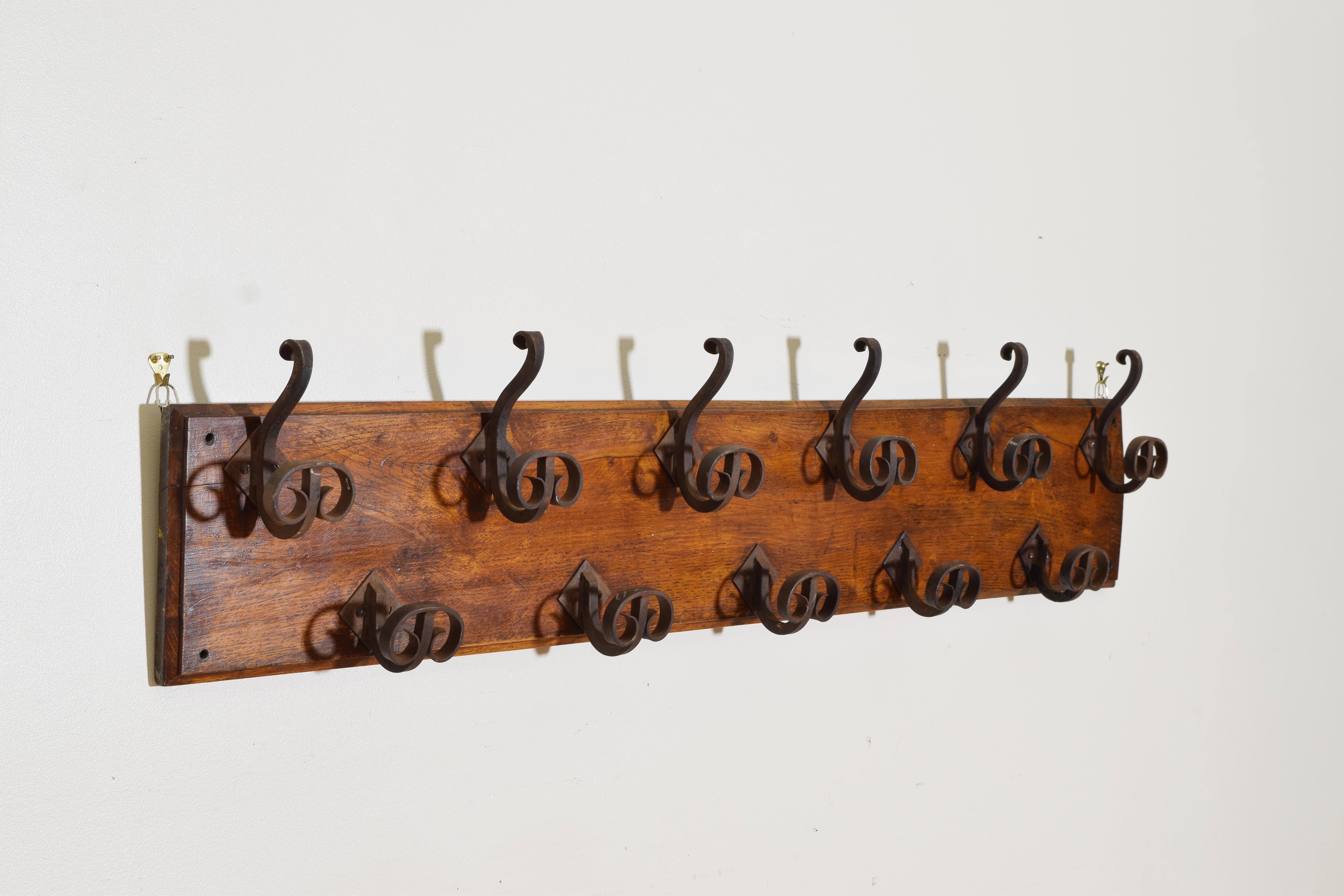 Having a rectangular backplate with an upper row of six wrought iron hooks and a lower row of five wrought iron hooks