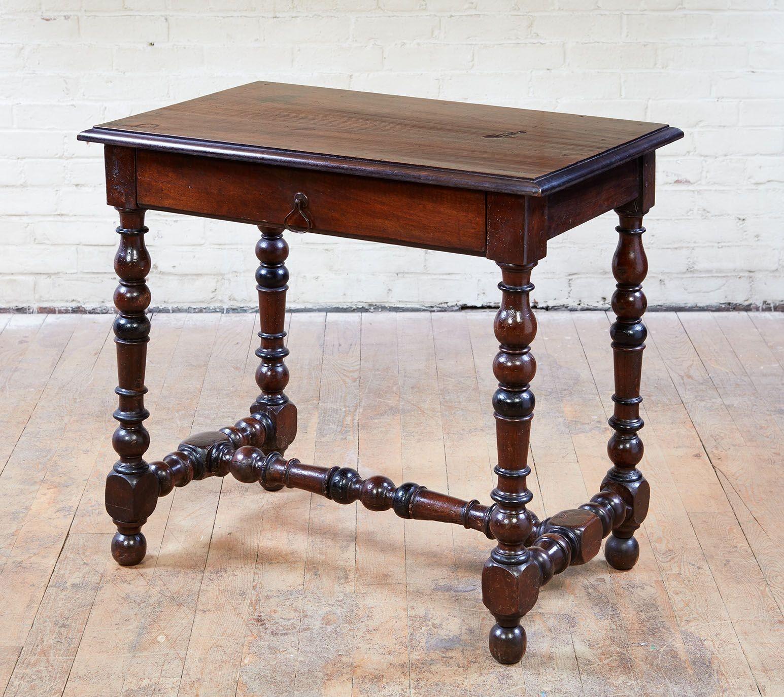 A French baroque single drawer side table in walnut having molded top above single drawer with triangular ring pull. Legs and stretcher retaining ebonized highlights and with particularly bold turnings, the whole possessing good color. Southern