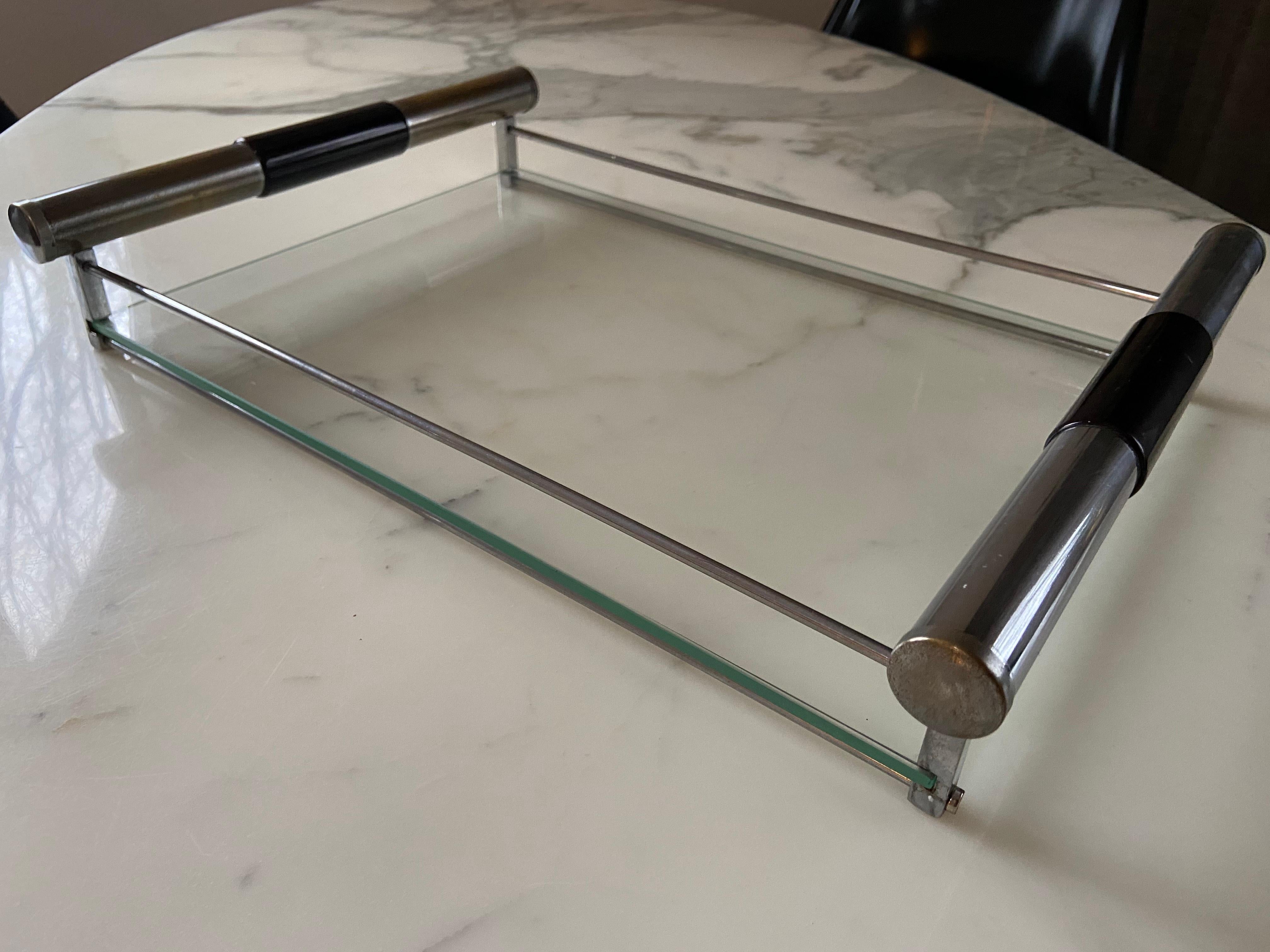 Dieses elegante und sehr seltene Serviertablett aus den 1930er Jahren ist ein Paradebeispiel für sich überschneidende und ineinander übergehende Designperioden, in diesem Fall vom Art déco zum Bauhaus.

Die quadratischen und runden Chromelemente des
