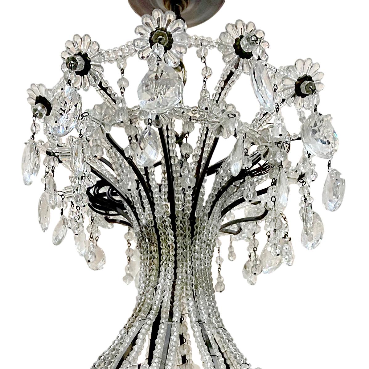 Ein großer französischer Perlenleuchter mit zwölf Lichtern aus der Zeit um 1920 mit Kristalleinsätzen am Korpus und aufgesetzten Kristallblumen.

Abmessungen:
Stromabfall: 46