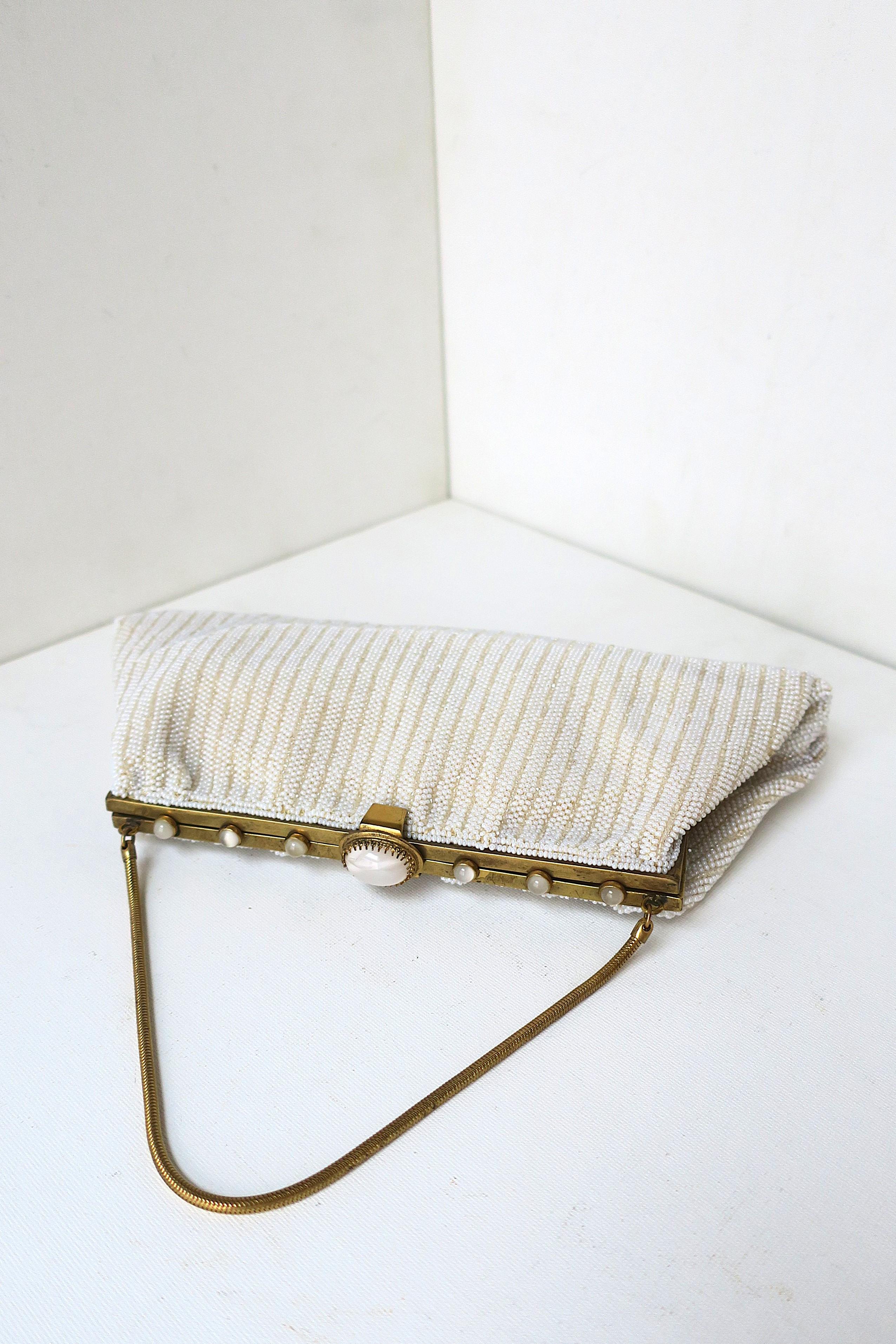 Un sac à main du soir français blanc orné de bijoux et de perles, avec fermeture en laiton et poignée flexible. Sept belles pierres naturelles rondes et ovales en cabochon tapissent le dessus de la fermeture en laiton. La doublure est en satin crème