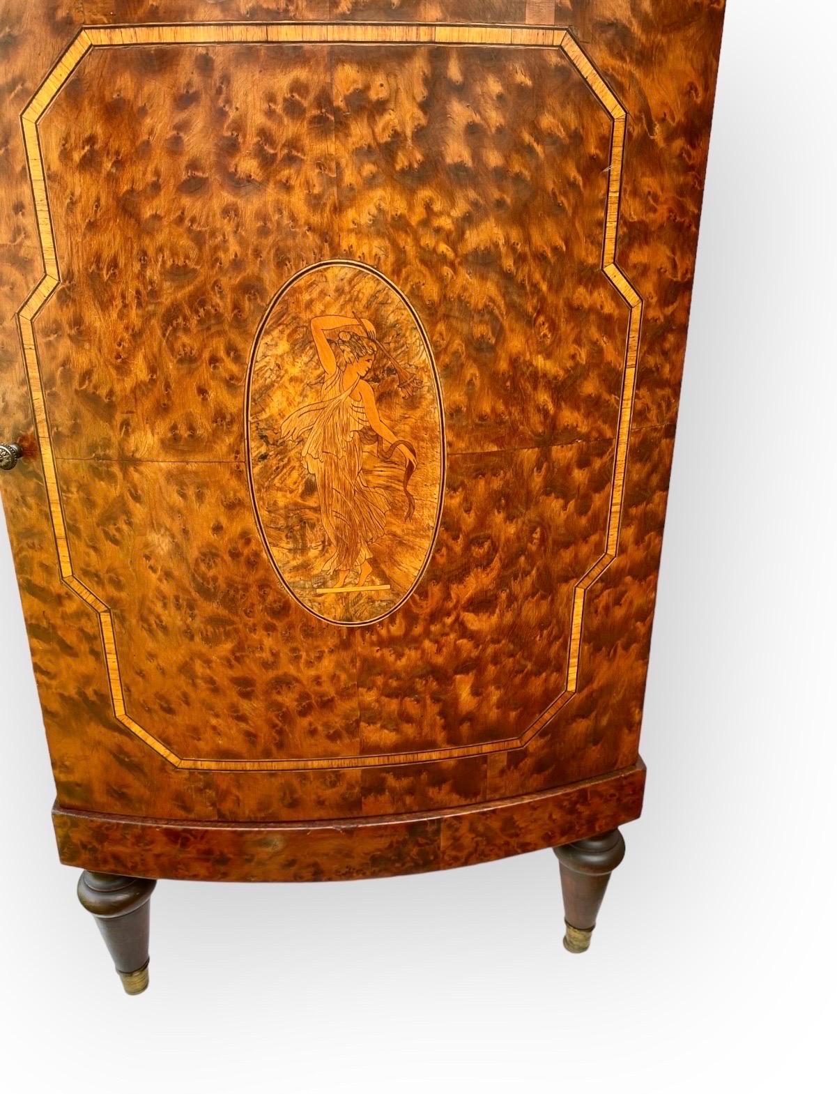 A handsome antique French Beaux Arts burl wood and exotic inlaid woods cabinet with a bowed, fixed marble top, a single bowed drawer and a single bowed door opening to a shelf and a marble lined compartment. The bowed door with a central marquetry