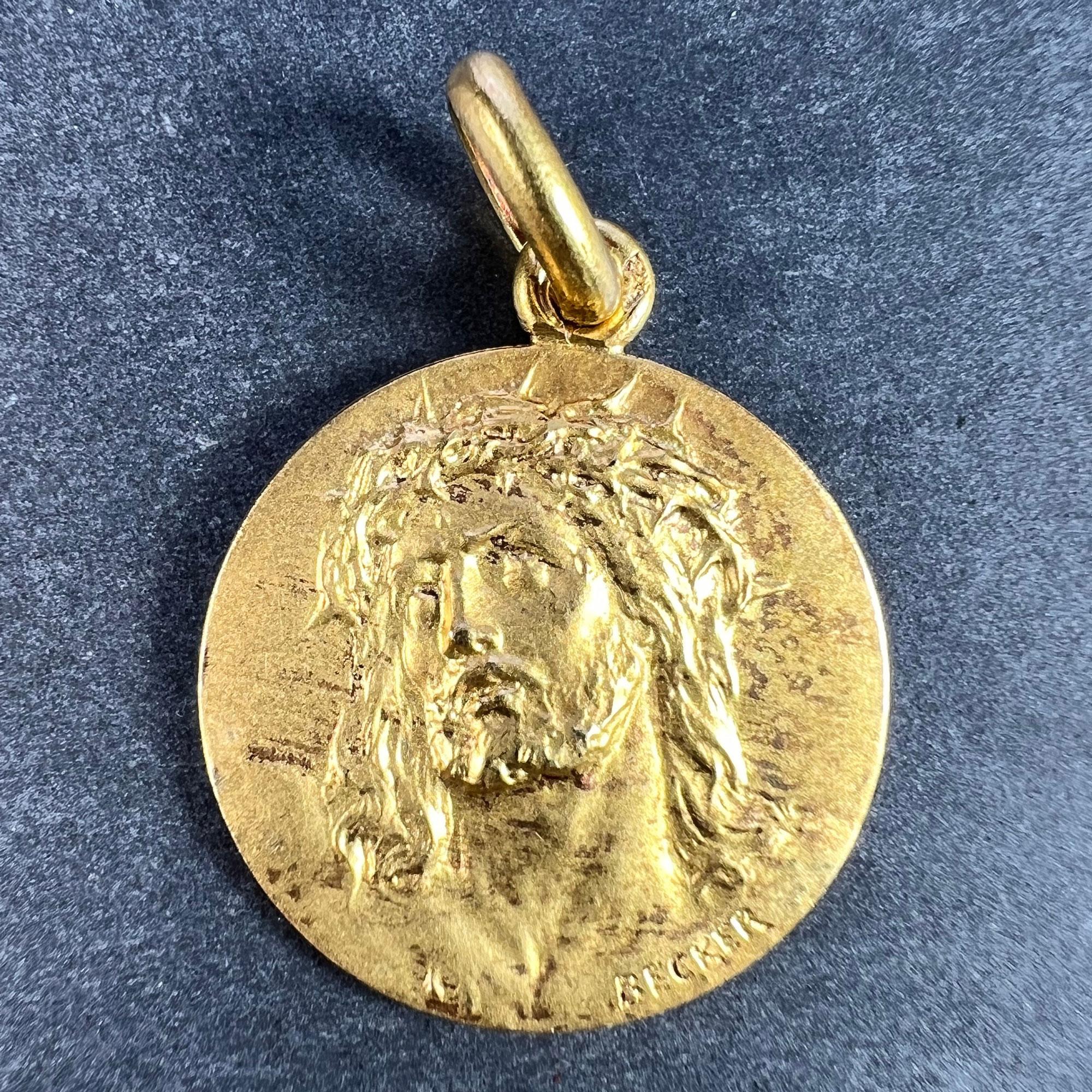 A French 18 karat (18K) yellow gold charm pendant designed as a round medal depicting Jesus Christ wearing the Crown of Thorns. Signed Becker, stamped with the eagle’s head for 18 karat gold and French manufacture, along with an unknown maker's