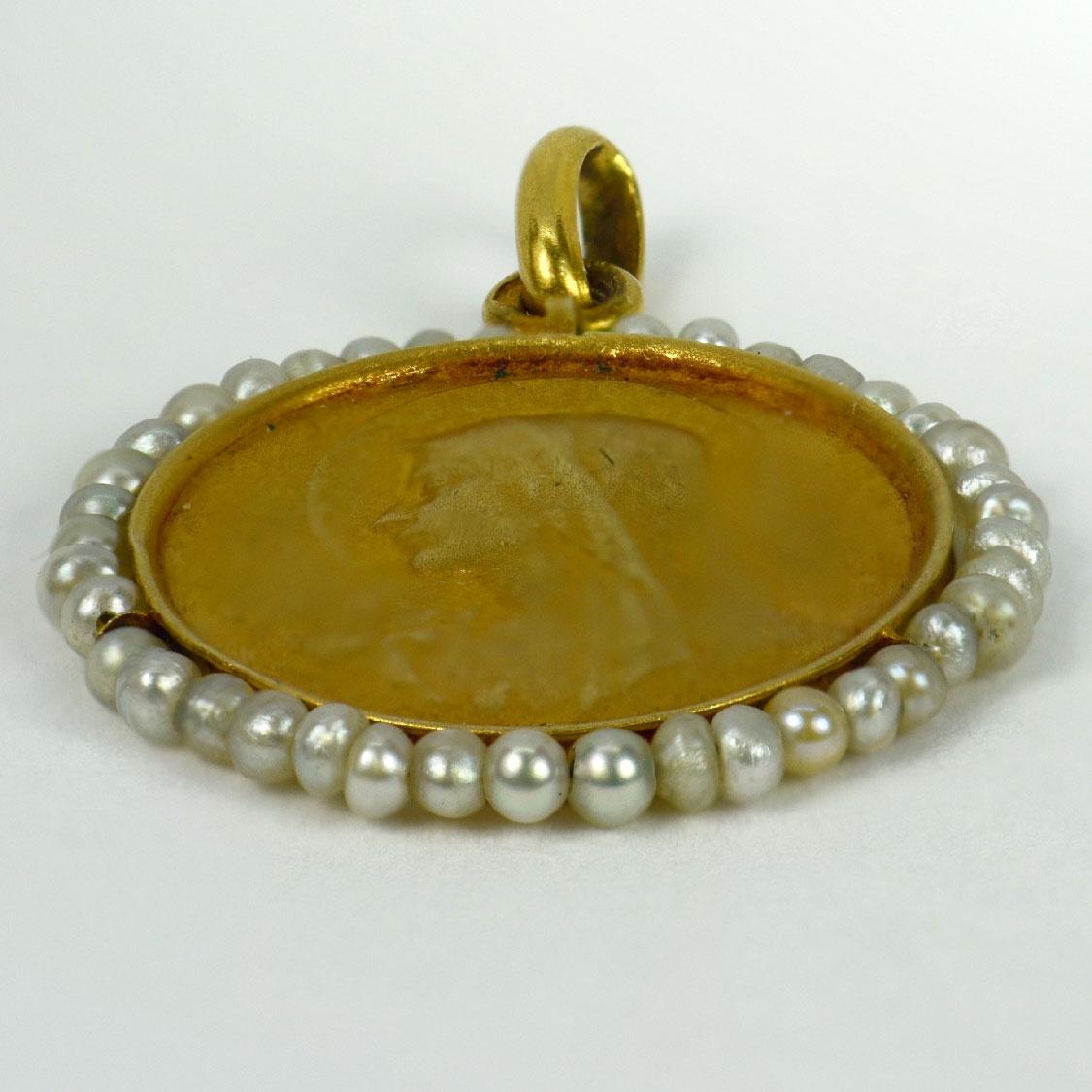 A French 18 karat (18K) yellow gold charm pendant designed as a disc representing the Virgin Mary with a lily to one side, and the holy dove to the other, surrounded by 39 natural white seed pearls. Signed Becker, stamped with the eagles head for