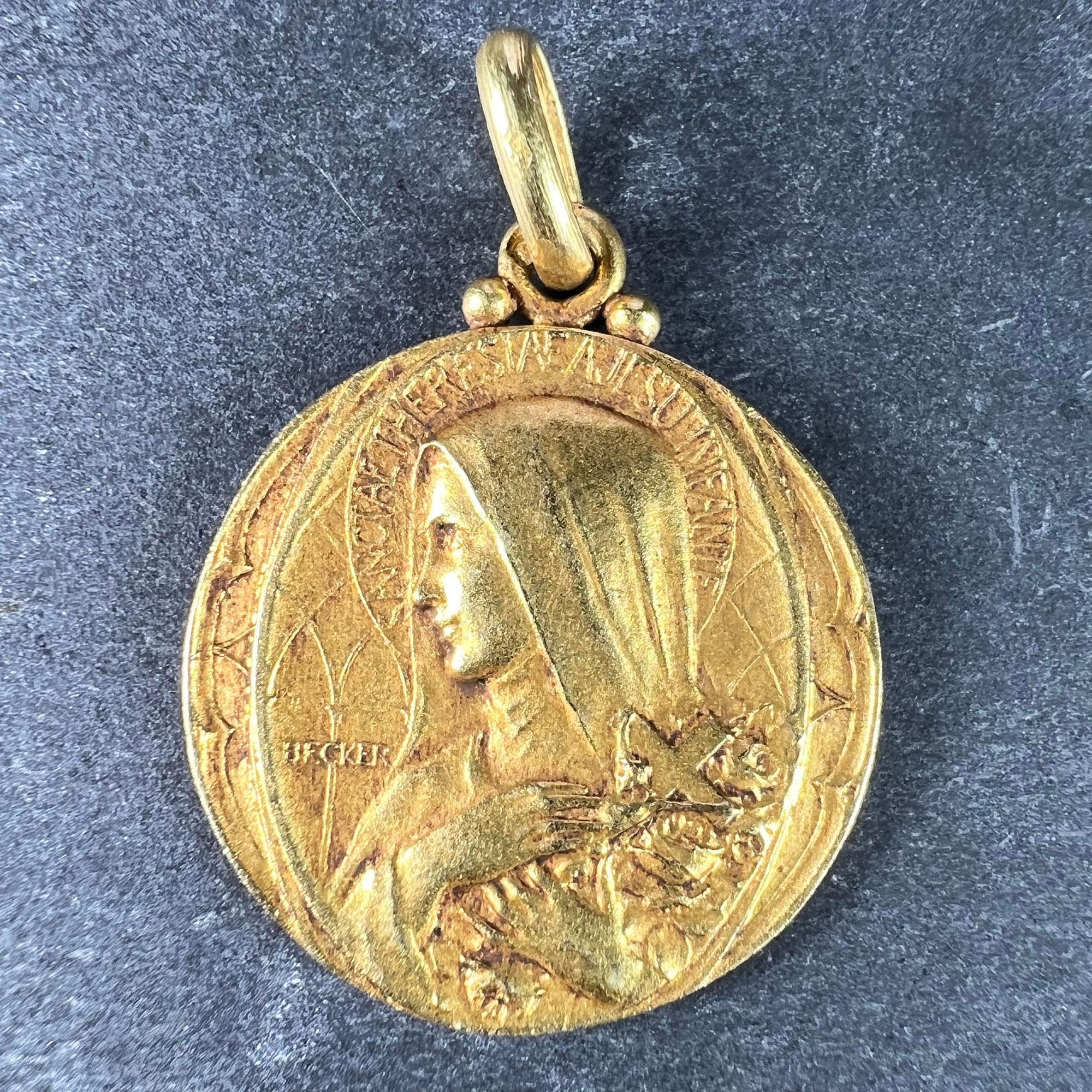 A French 18 karat (18K) yellow gold charm pendant designed as a medal depicting Saint Therese with a halo with the phrase 'SANCTAE THERESIAE A JESU INFANTE' (Saint Therese of the Infant Jesus) holding a crucifix and some roses, the surround with