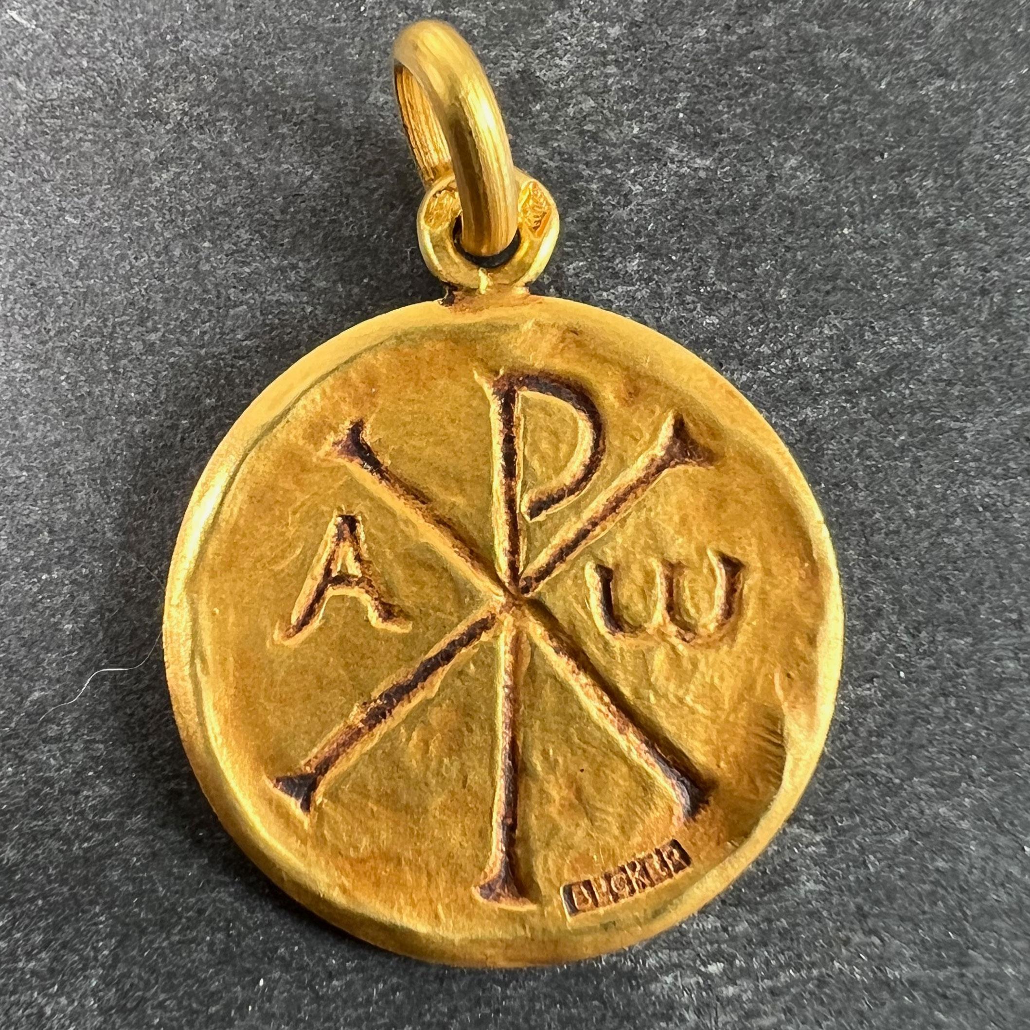 A French 18 karat (18K) yellow gold charm pendant designed as a medal depicting the symbol for Chi Rho with the letters Alpha and Omega (all being symbols of Jesus Christ). The reverse engraved 'Laurent Combet' with the dates '23.8.1969' and
