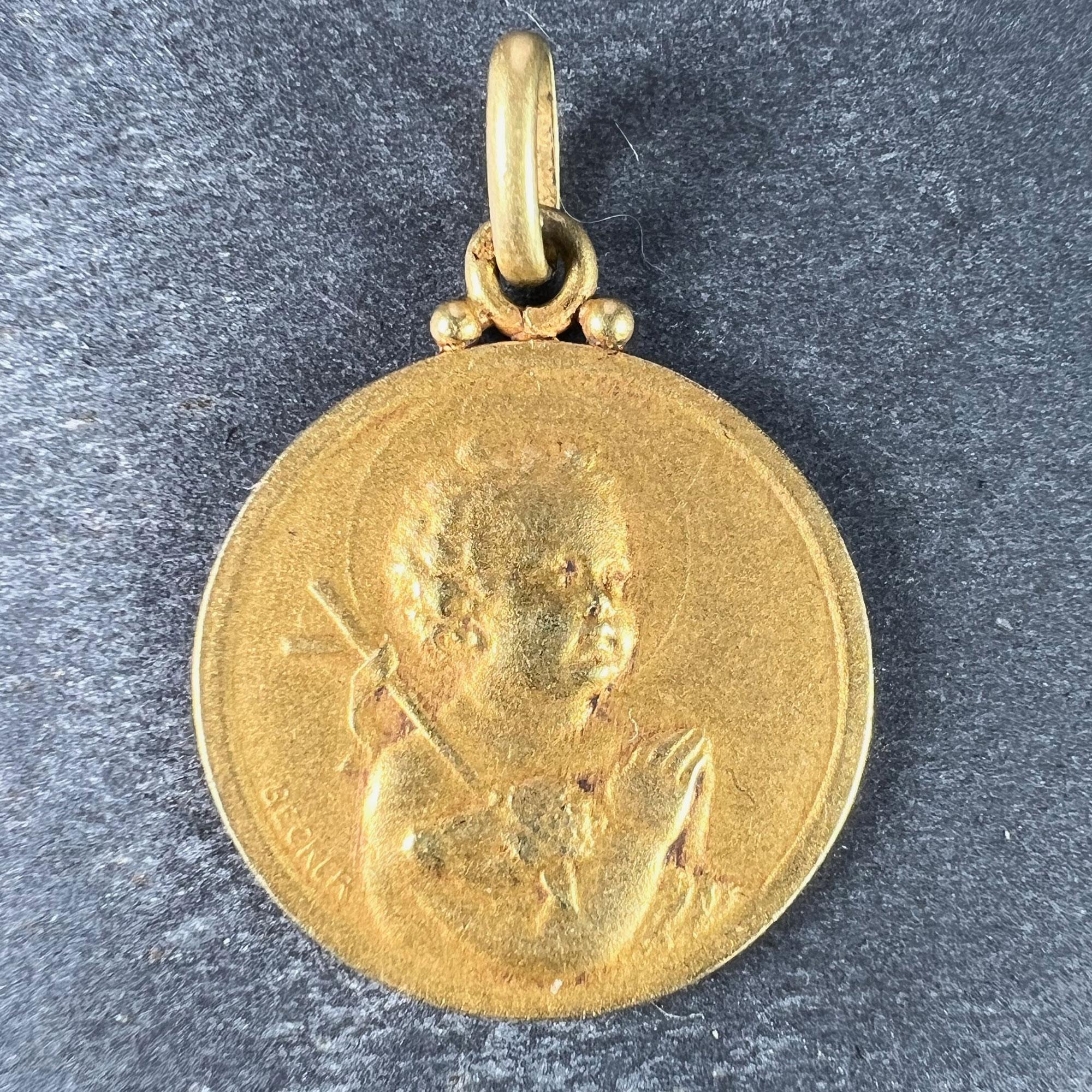 A French 18 karat (18K) yellow gold charm pendant designed as a medal depicting the Jesus Child holding the Lamb of God and a shepherd's crook while praying. The reverse shows the top of a column with roses surmounting it. Signed Becker and stamped