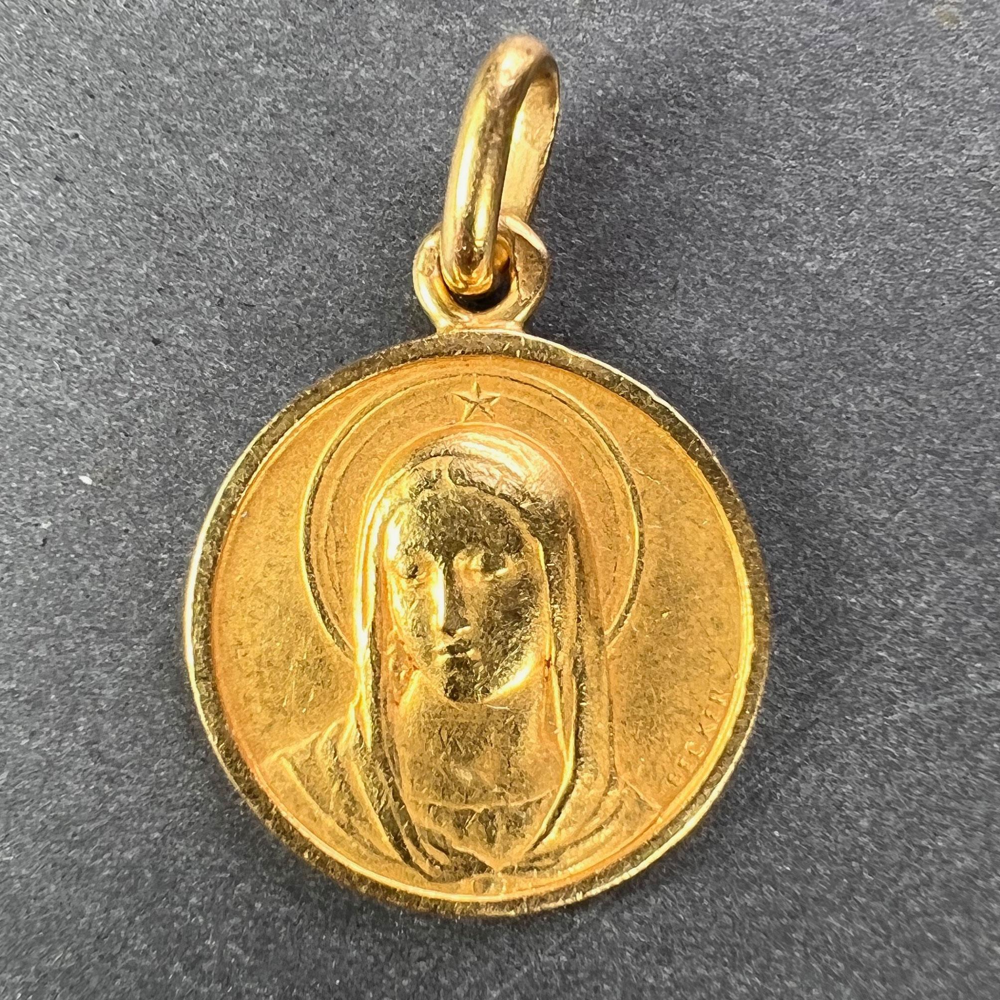 An 18 karat (18K) yellow gold charm pendant depicting the Virgin Mary. Engraved to the reverse with the date 23 Juin 1957. Signed Becker and stamped with the eagle mark for 18 karat gold and French manufacture with an unknown makers