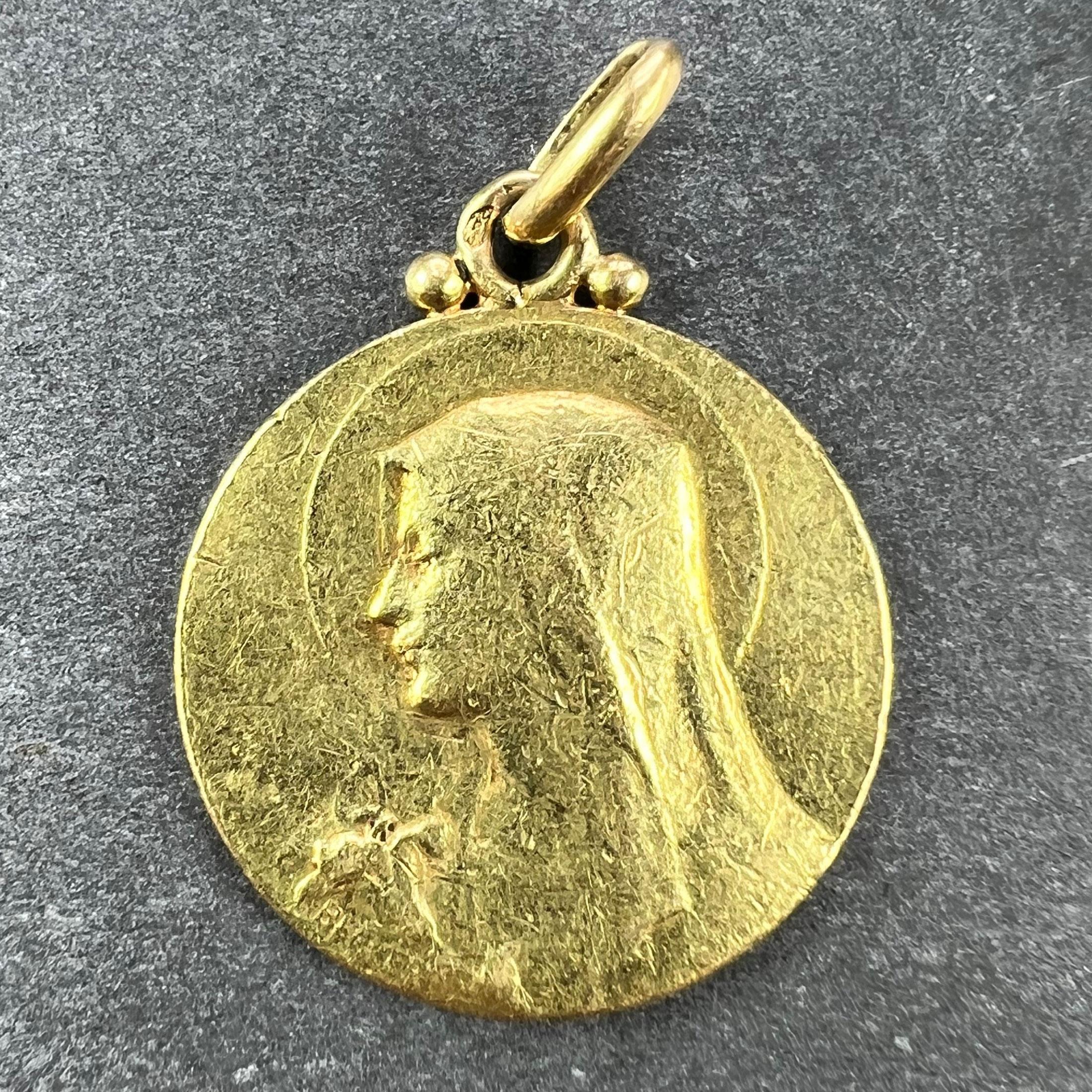 A French 18 karat (18K) yellow gold charm pendant designed as a medal representing the Virgin Mary with a lily to one side, and the holy dove to the other, engraved with a monogram RB/BR and the date 5 Aout 1926. Signed Becker, stamped with the